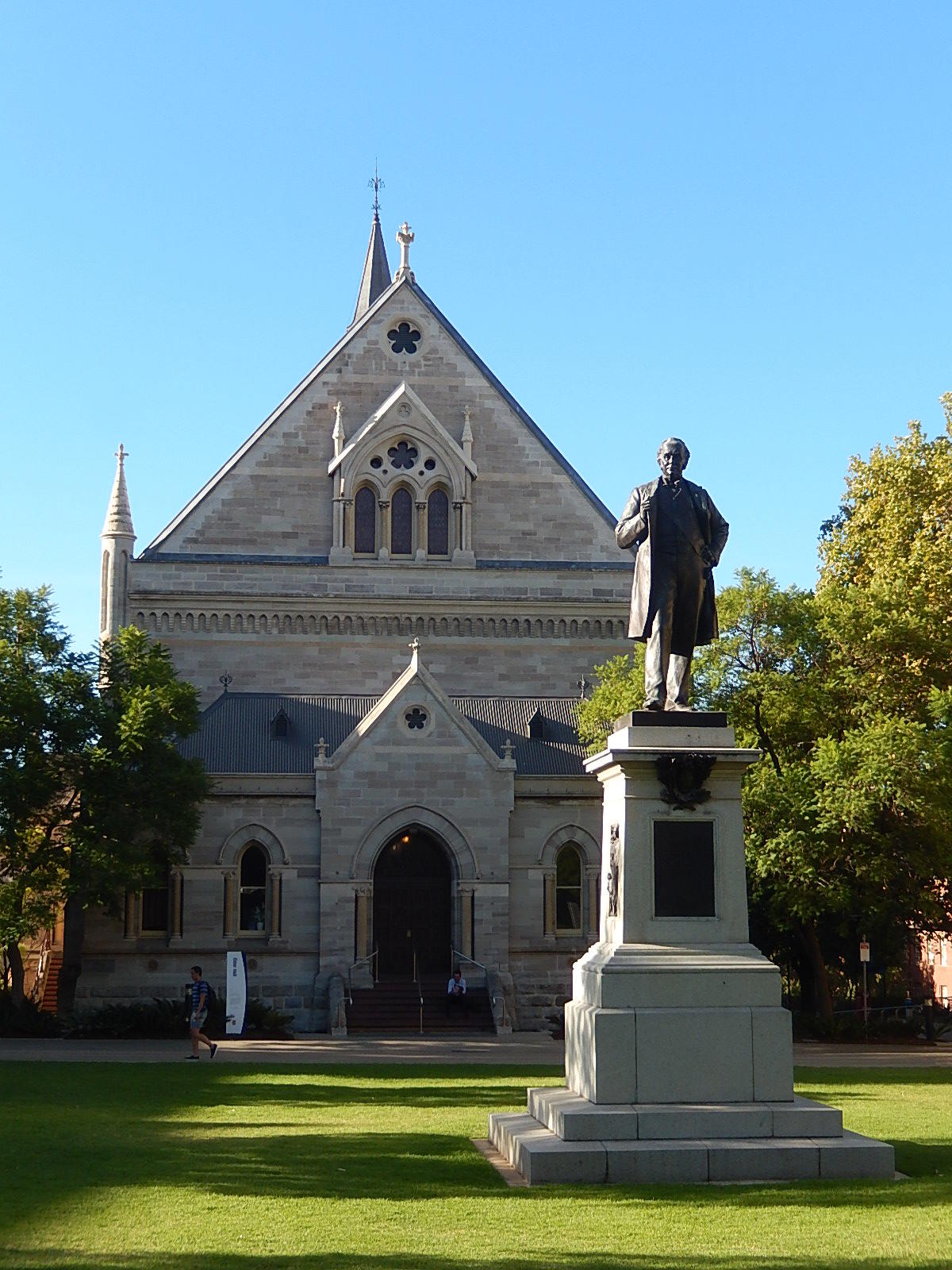 A stone building with a statue in front on a sunny day. 