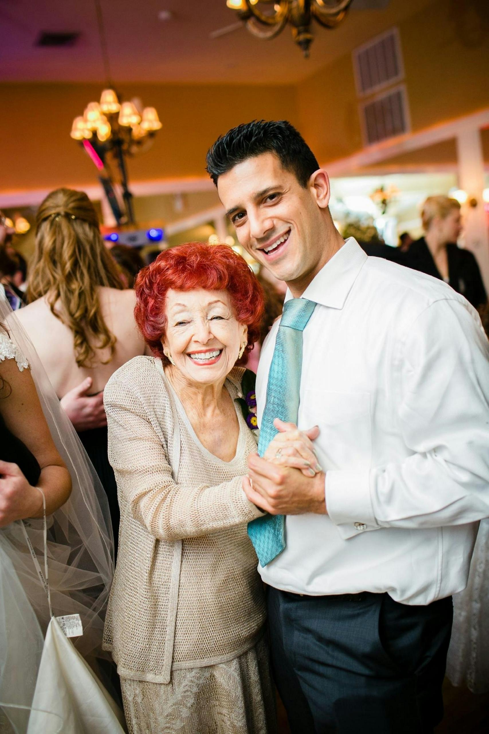 A young man dances with an elderly woman.