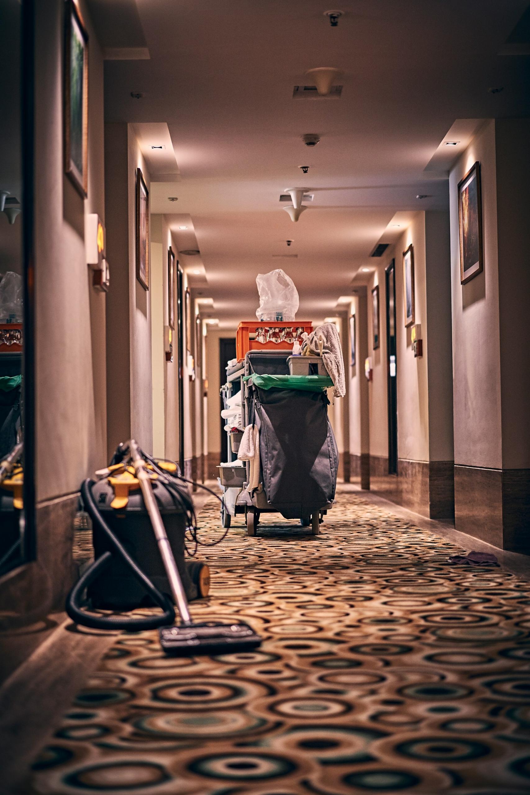 A maid's cart and hoover in a hotel hallway.