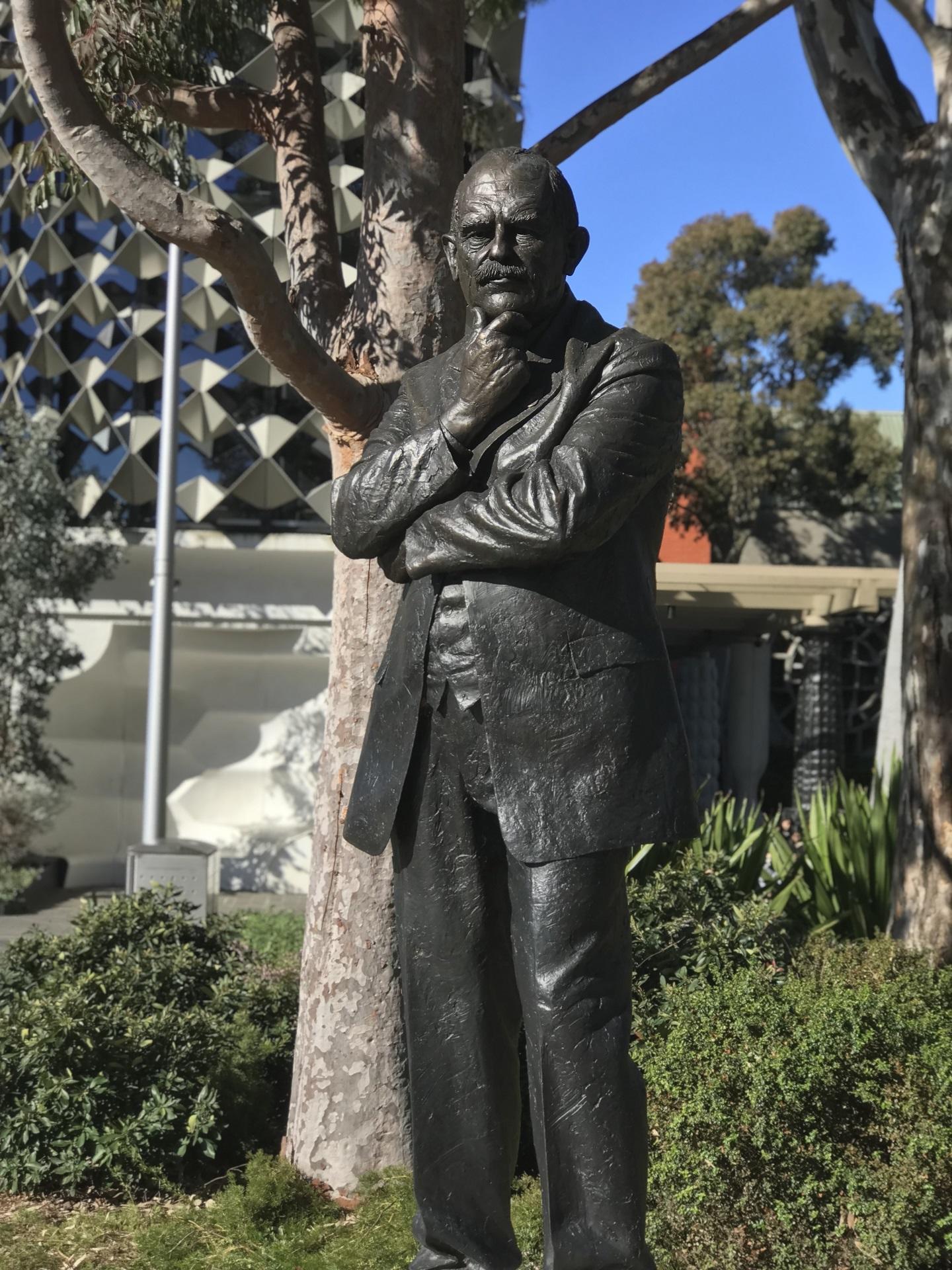 A statue of a man with his hand on his chin on a suny day.