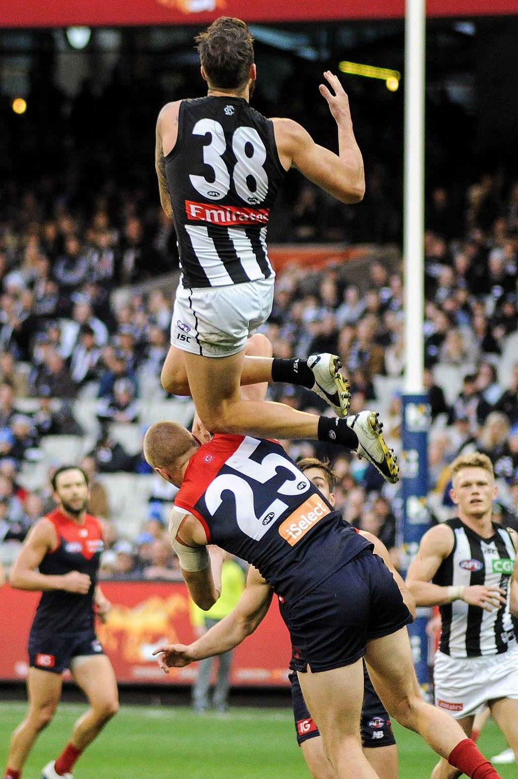 An AFL player marking over an other player during a game.