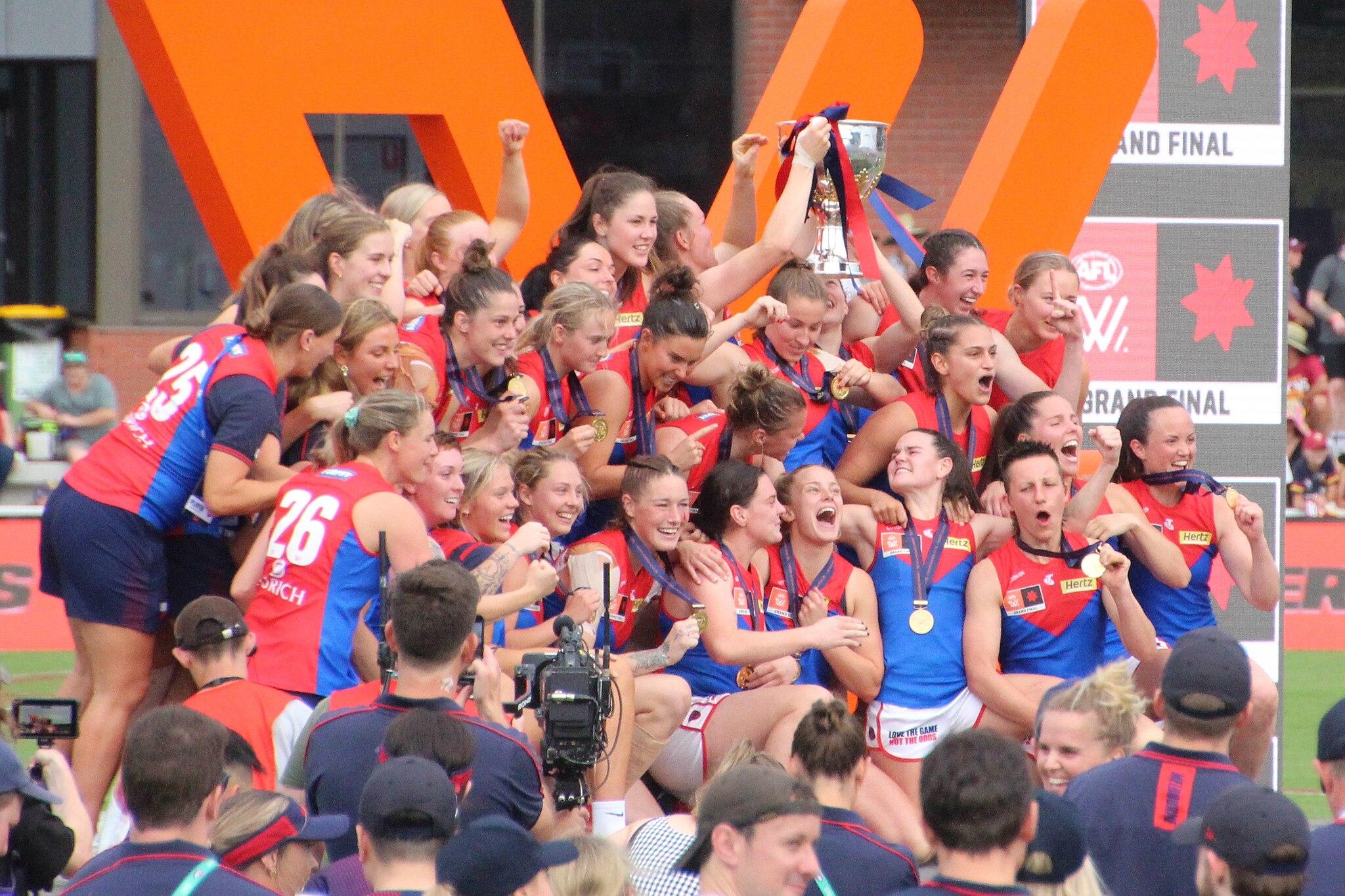 A women's AFL team celebrates together.
