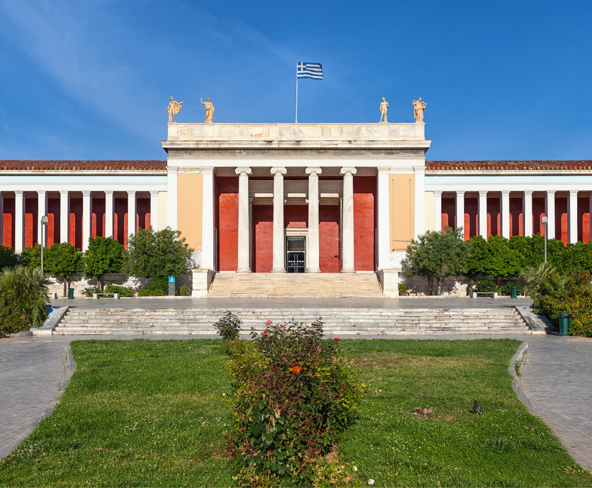 A red and yellow building behind a green lawn on a sunny day. 