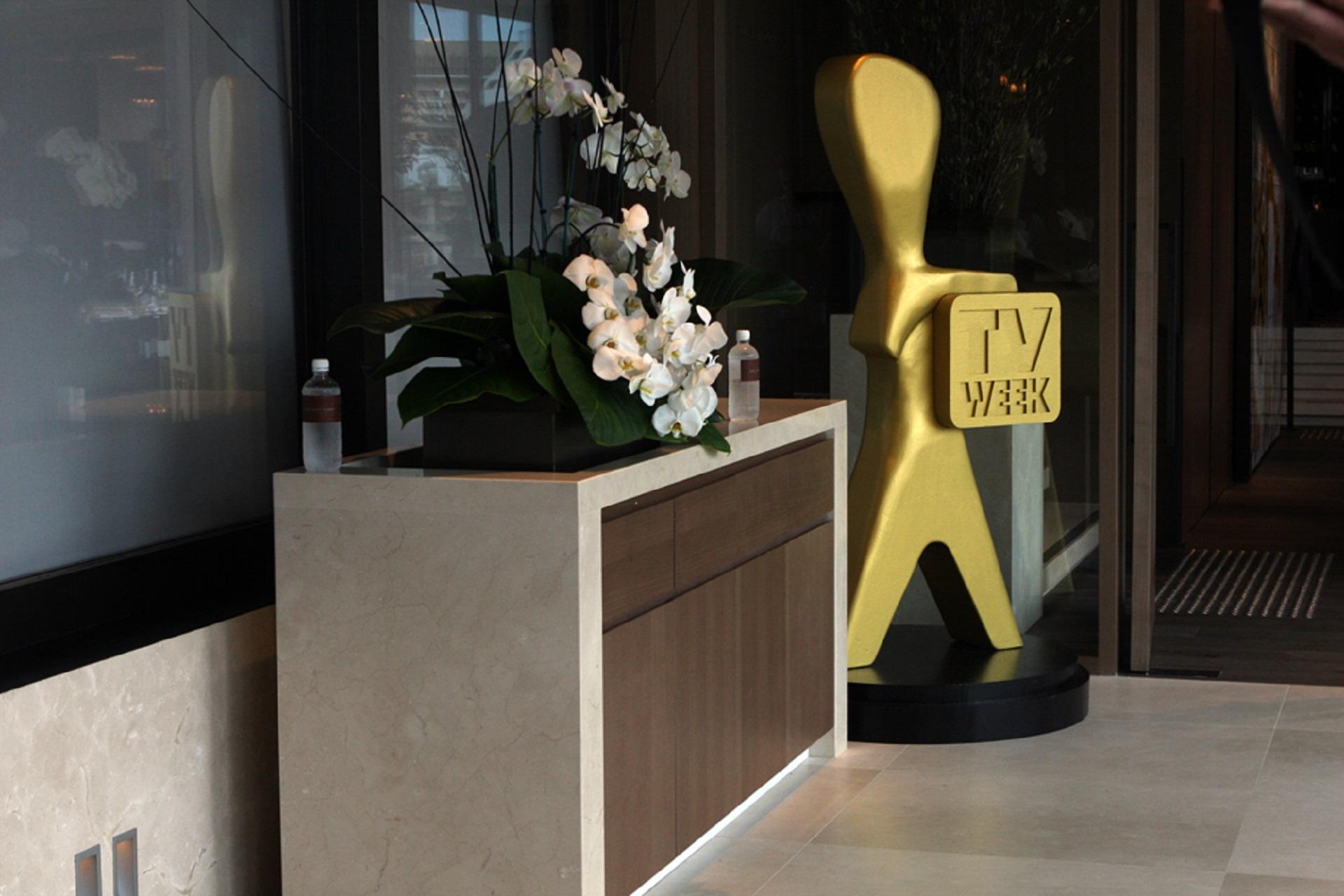 A golden statue stands to the side of a modernist credenza.