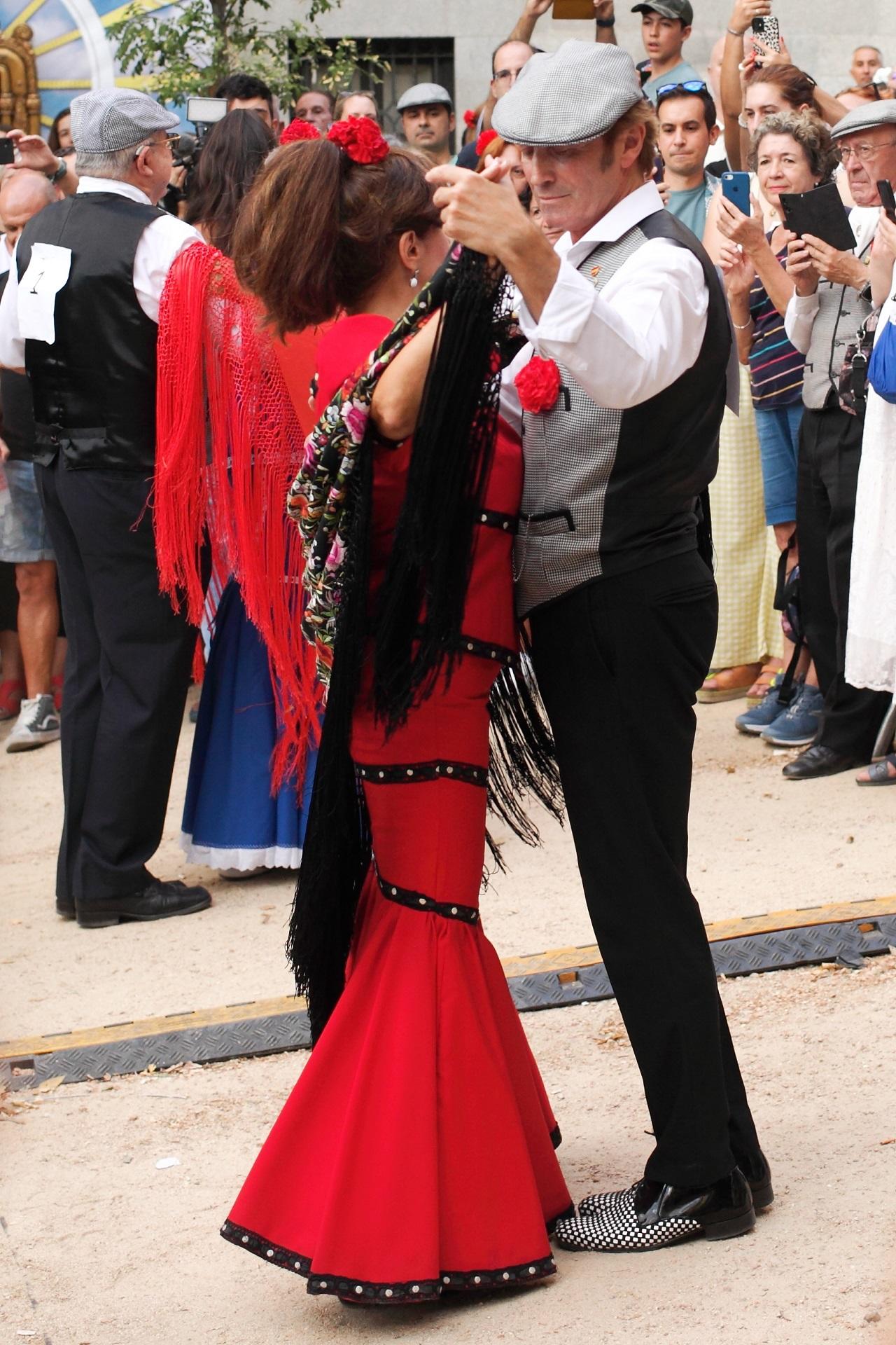 A man and a woman wearing costumes dance outside on a sunny day. 