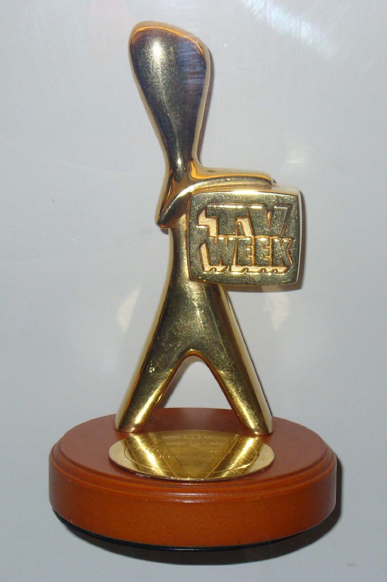 A gold statuette on a shiny wooden base.