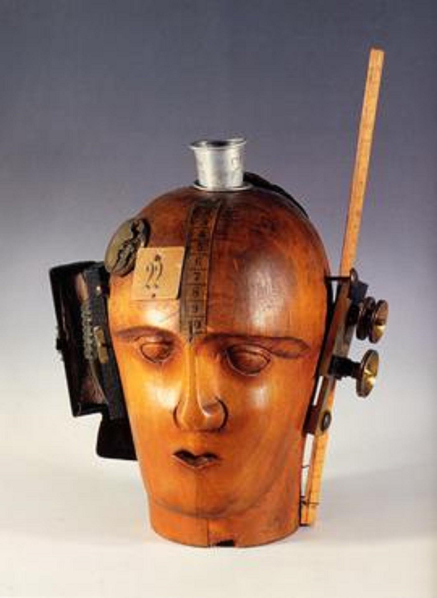 A wooden head with various items attached to it. 