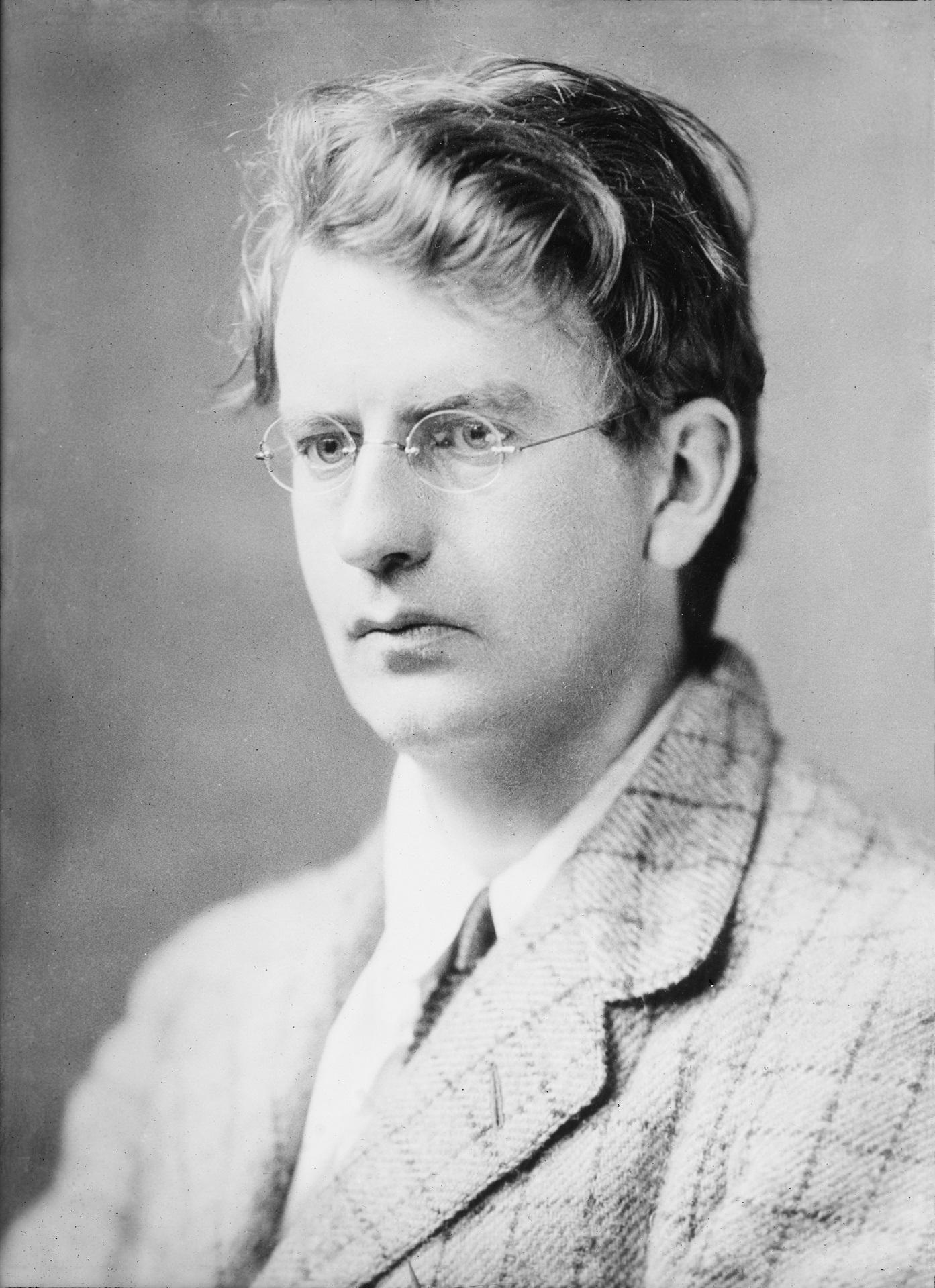 A greyscale image of a man wearing glasses. 