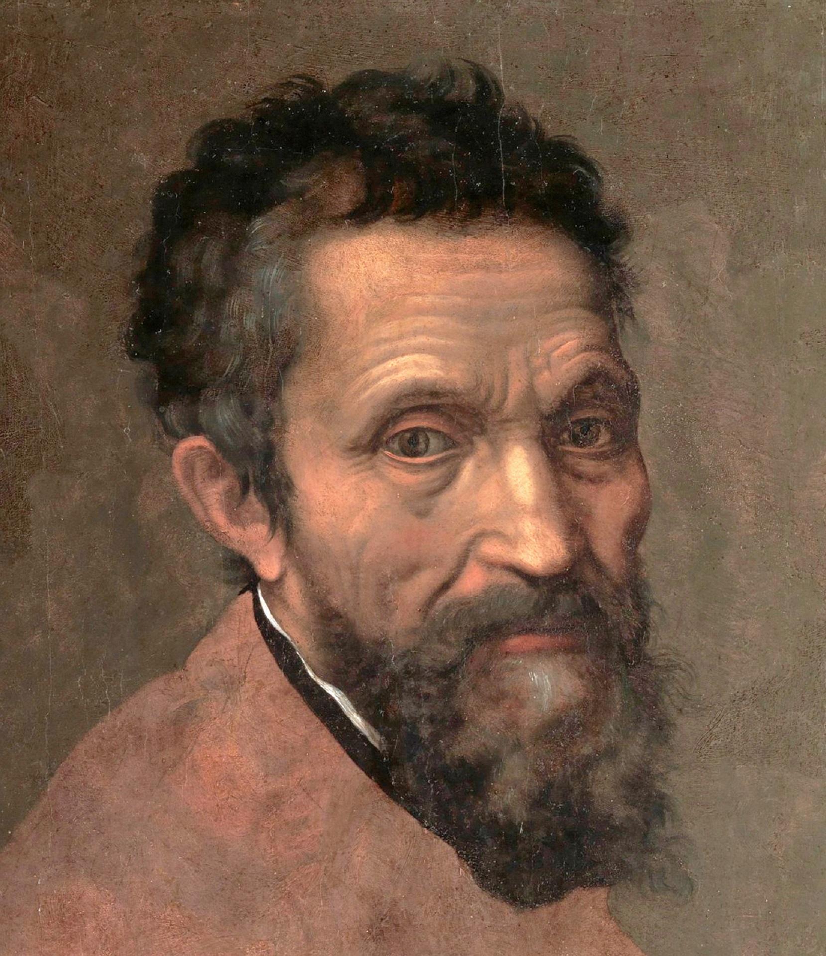 A portrait of a man with brown hair and a beard, wearing a light-coloured top.