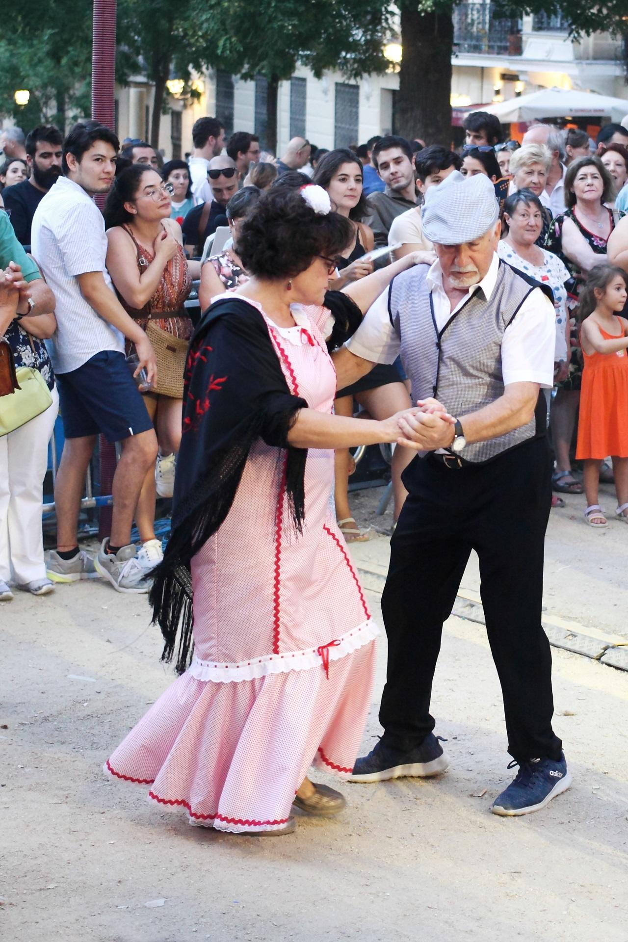 A couple dances outdoors while others look on. 