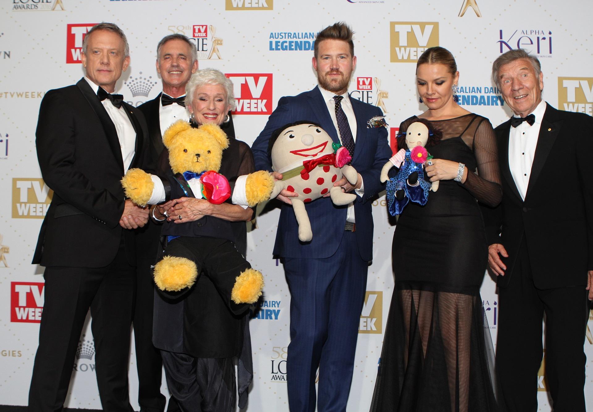 A group of people in formal wear holding plush toys.