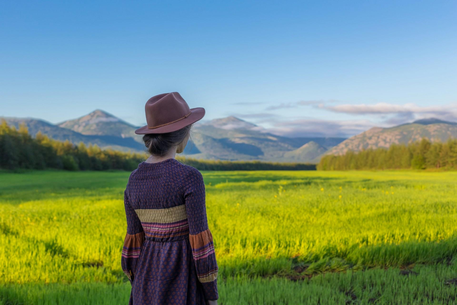 A woman in a purple dress in a field on a sunny day. 