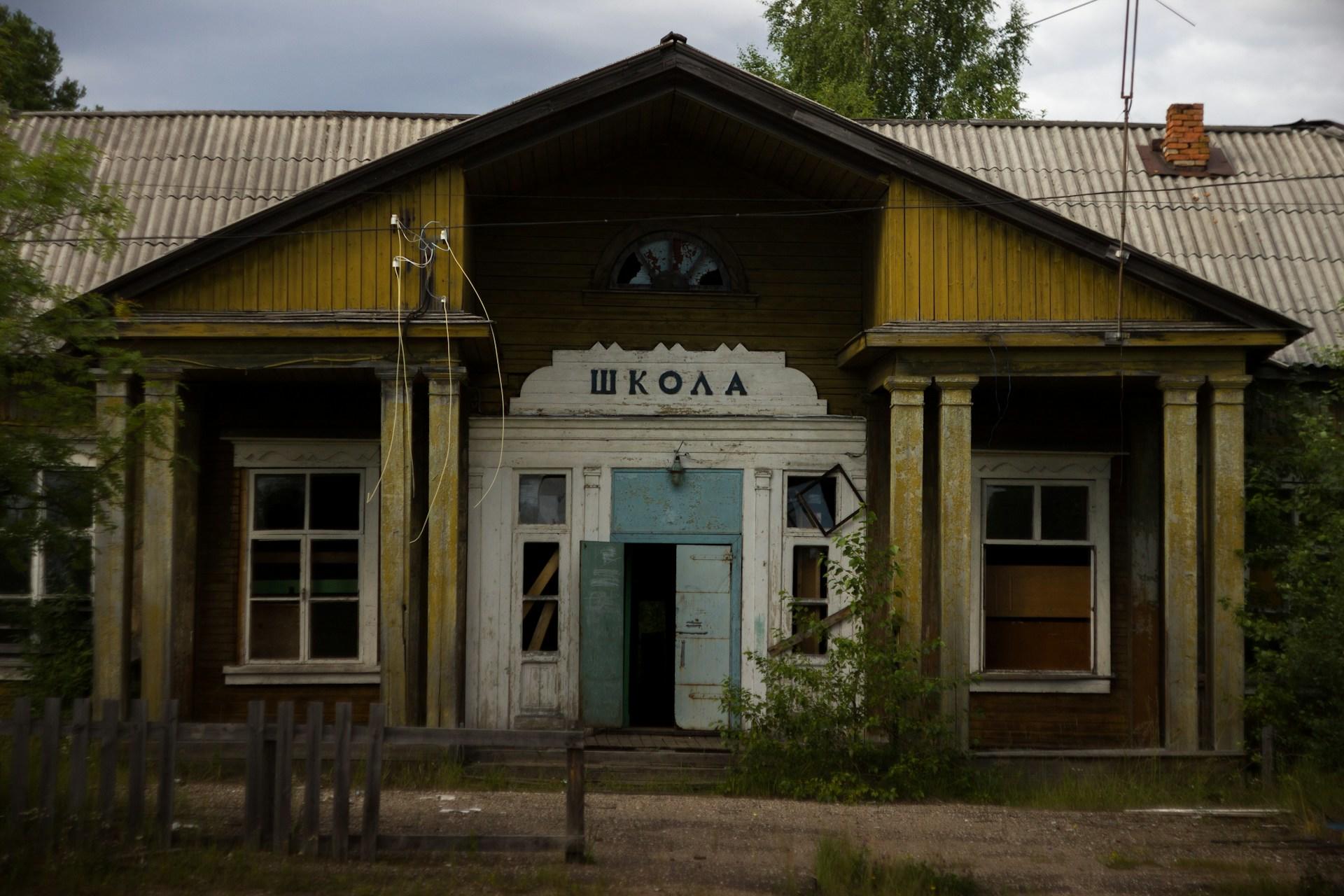 An old building with Russian writing above the door on a cloudy day. 