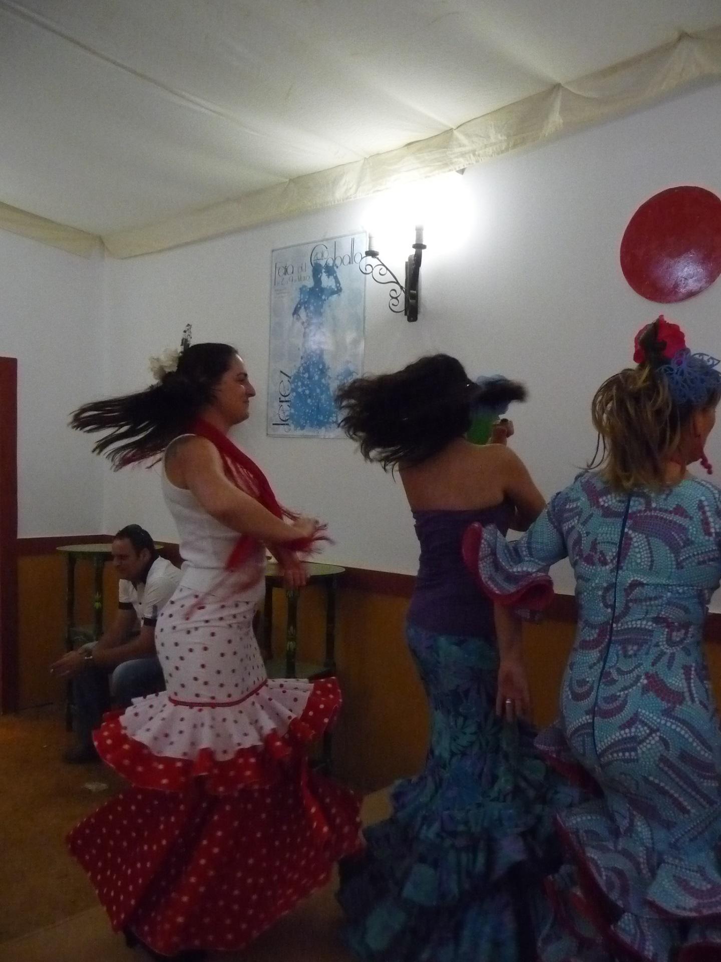 Women in long dresses twirl as they dance. 