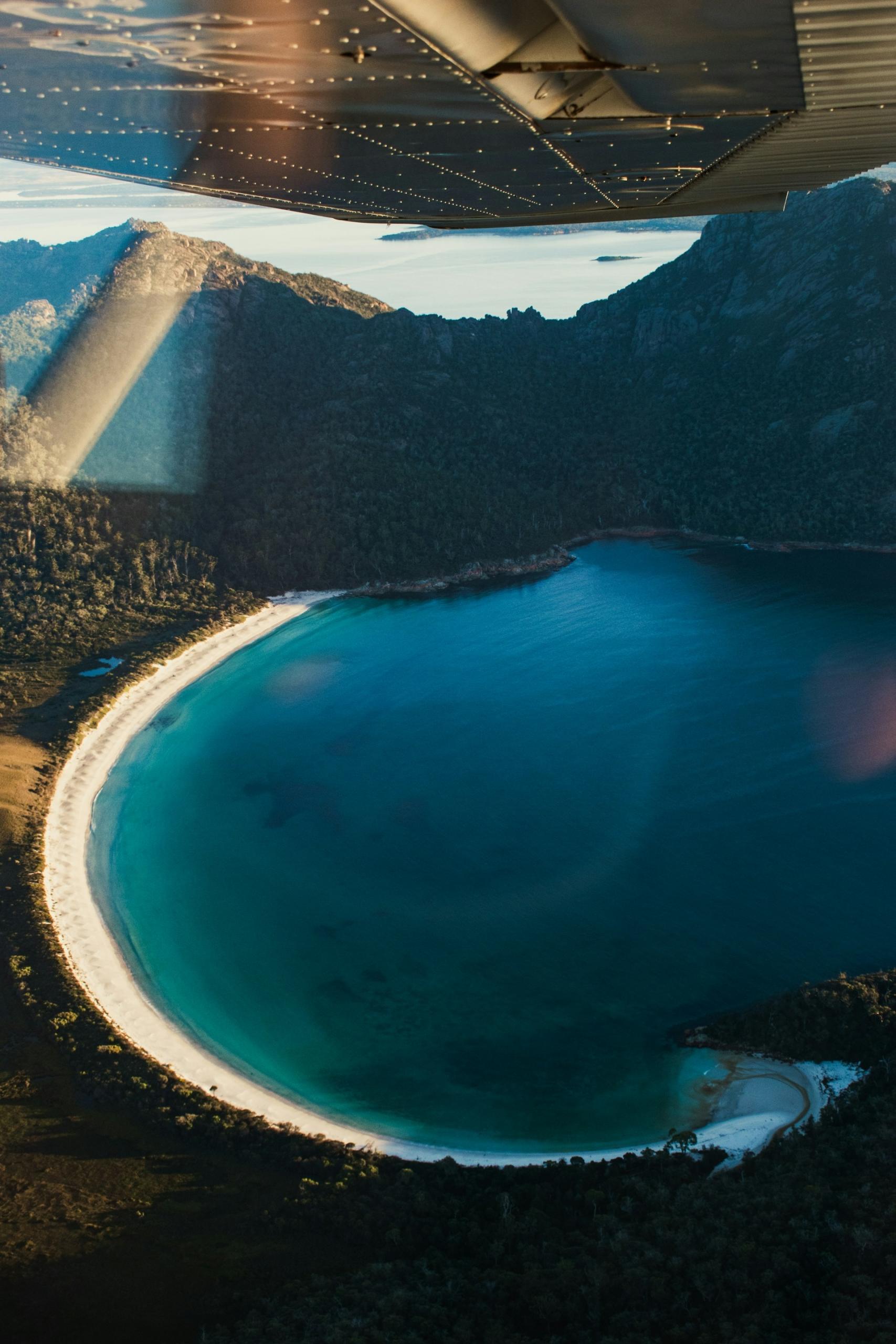 An aerial view of a body of water and a white strand on a clear day. 