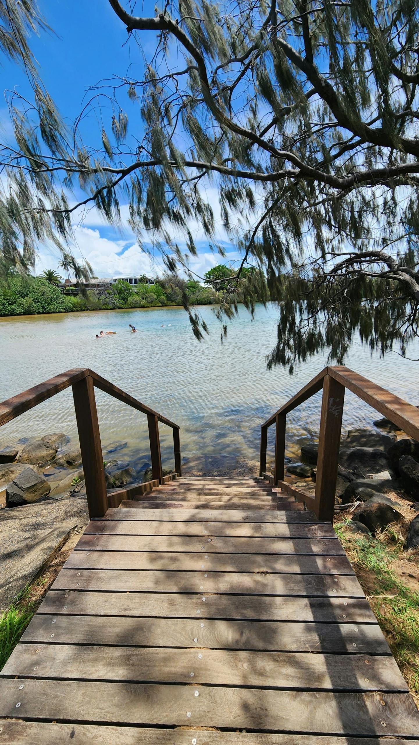 a plank walkway leading down to a beach on a sunny day. 