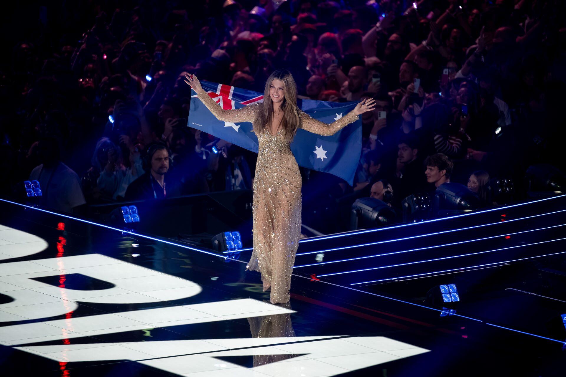 Delta Goodrem on stage holding an Australian flag