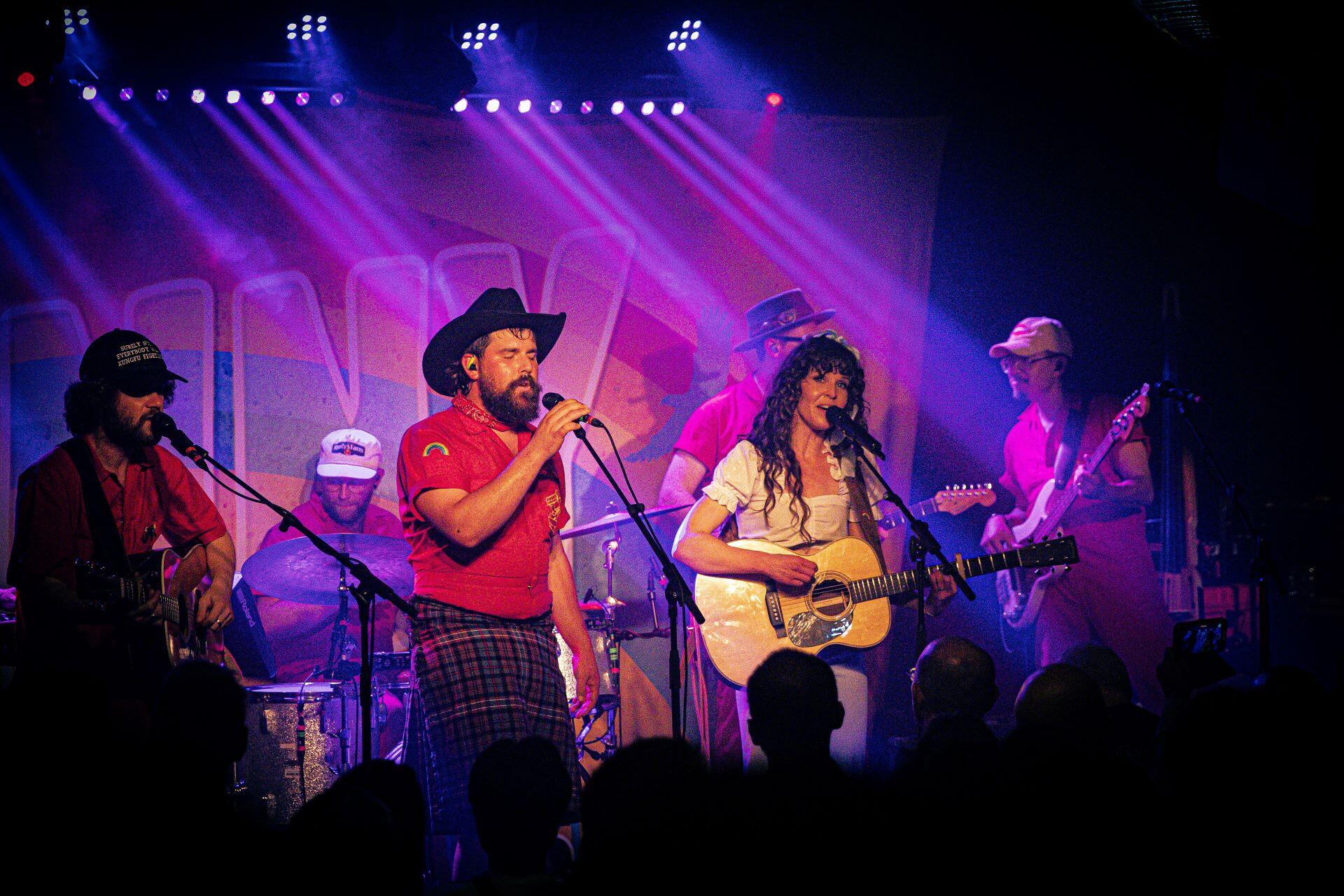Fanny Lumsden singing and playing acoustic guitar with her band on stage at The Lexington in London.