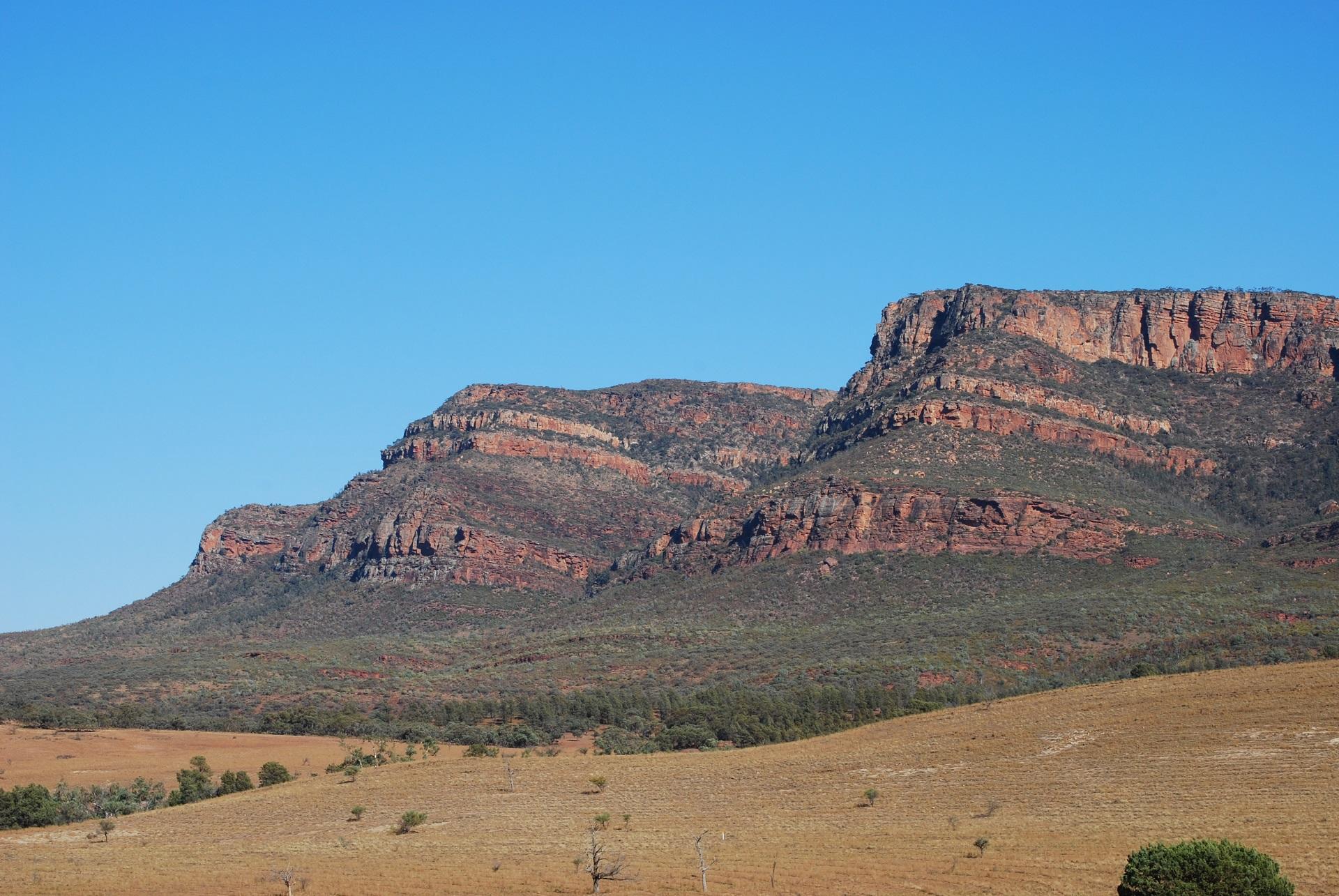 Mountains towering over barren land in daylight. 
