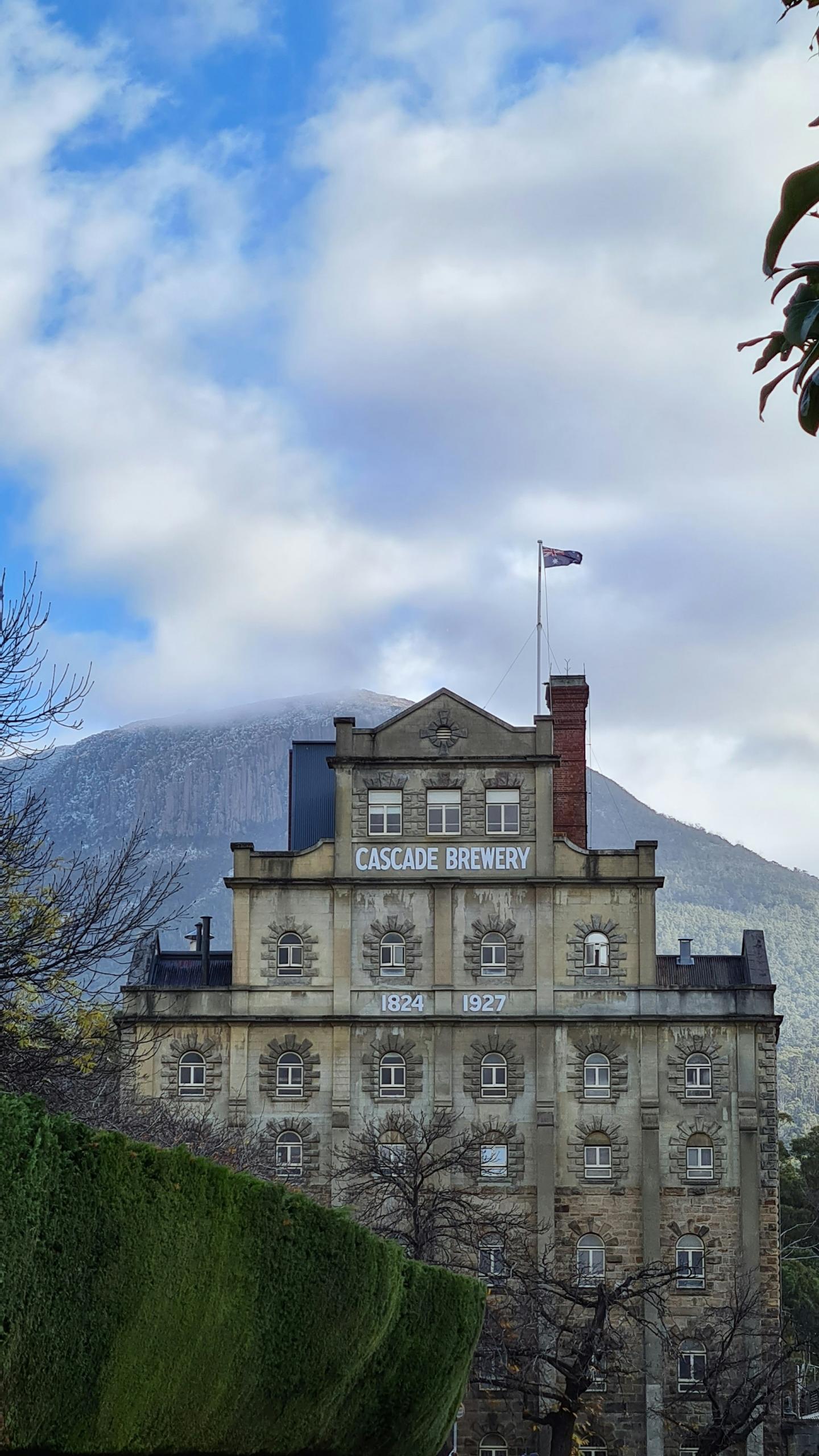 A stone building with a mountain in the background on a sunny day. 