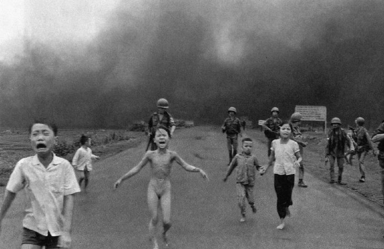 A greyscale image of terrified children running away from a cloud of smoke.