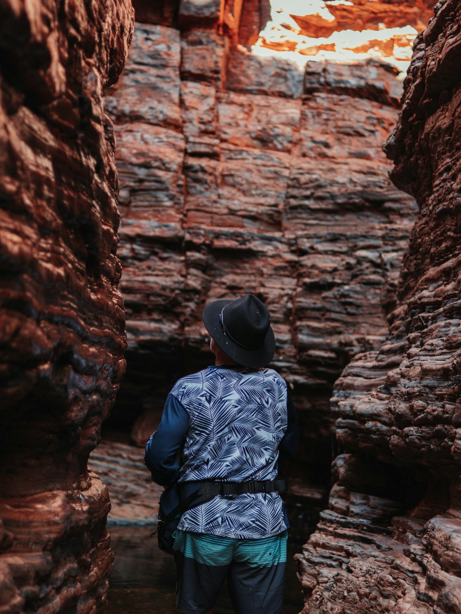 A person walks between high red cliff walls. 