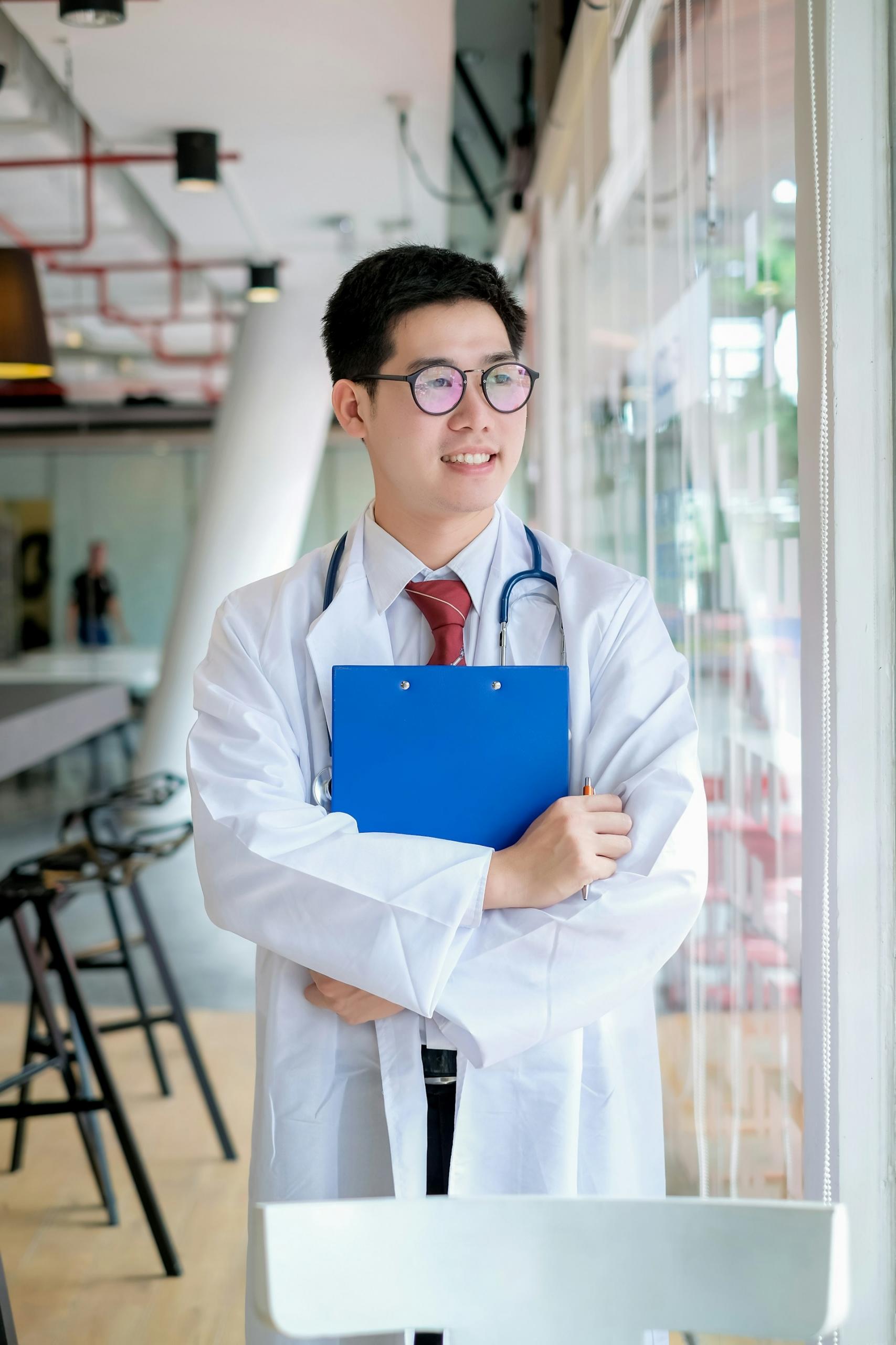A man in a white labcoat holds a blue clipboard