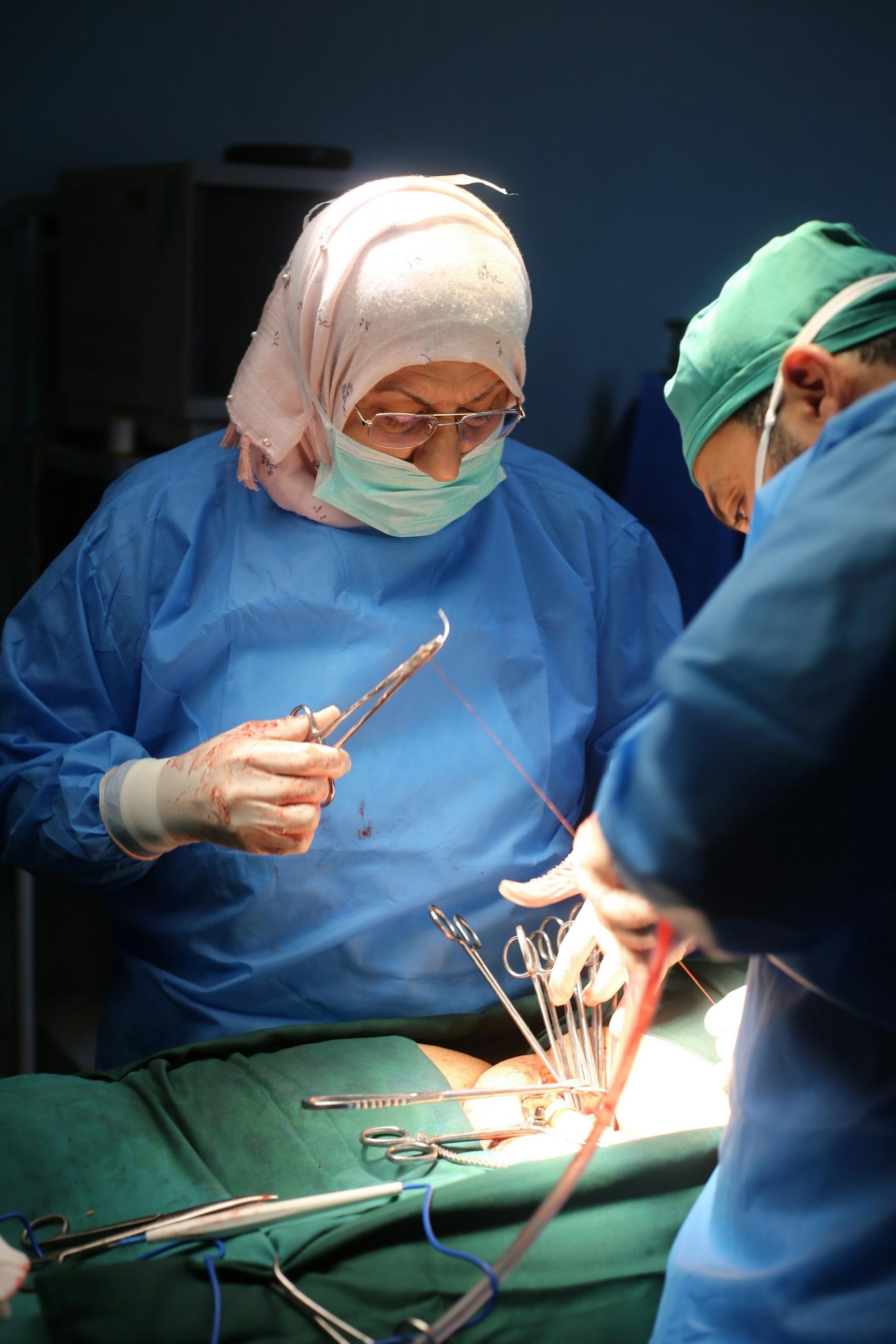 Two people in blue surgical scrubs wearing masks.