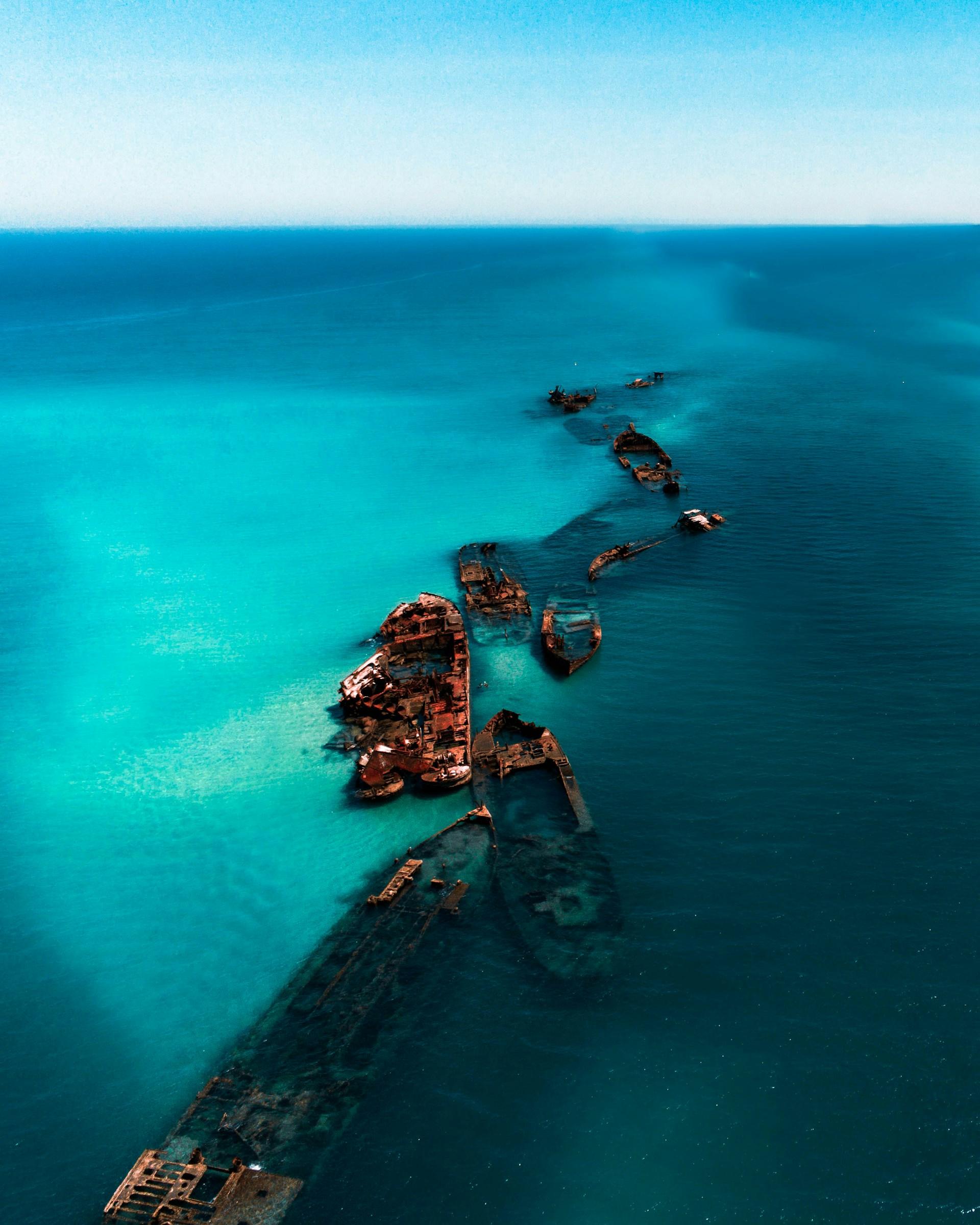 A string of sunken ships in a blue water body on a sunny day. 
