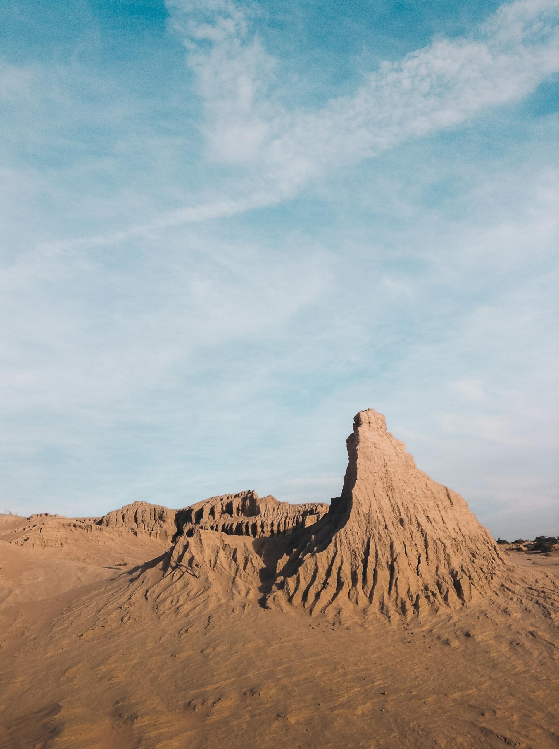 A red desert featuring a formation under a sunny sky. 