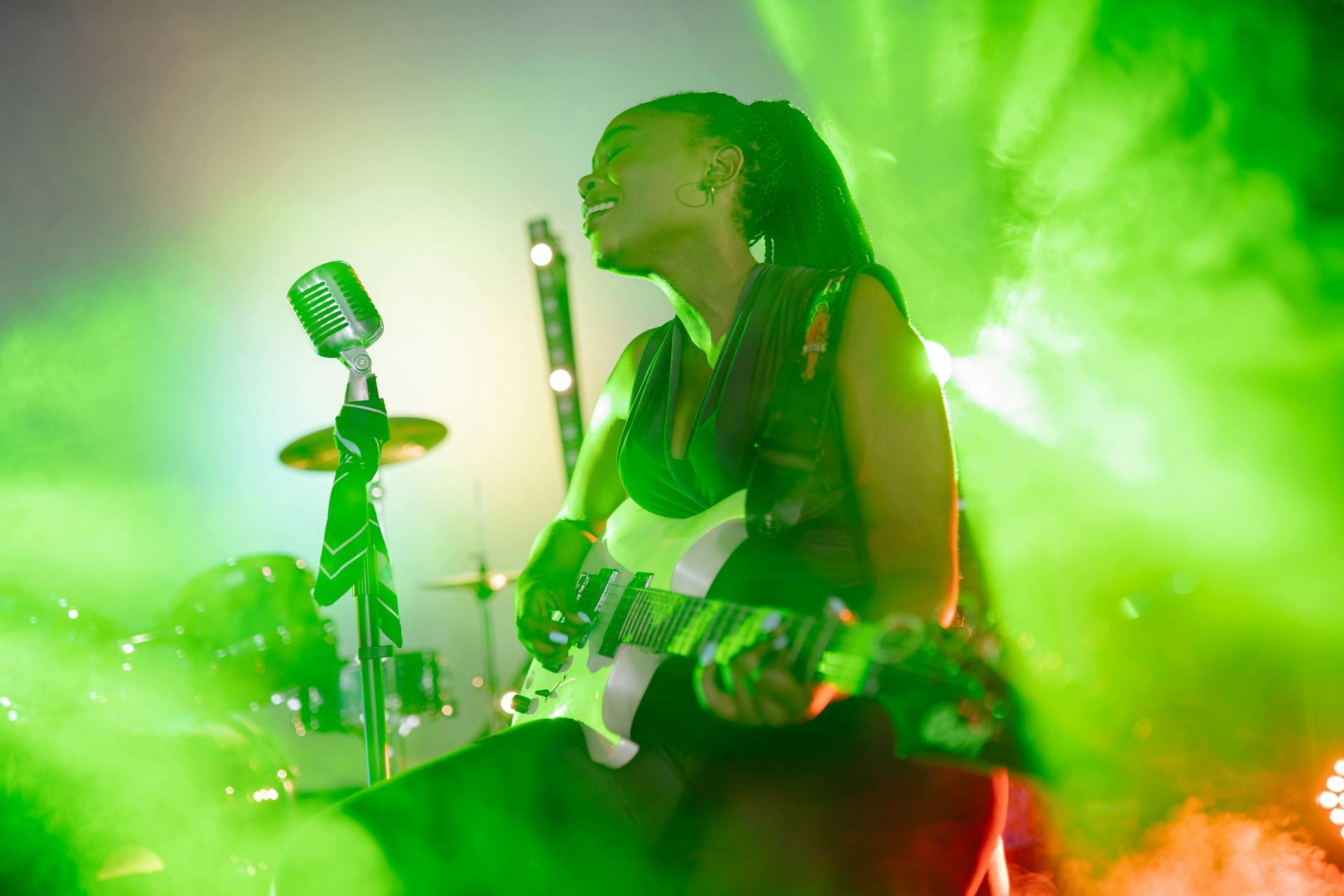 a guitarist singer on stage with green lights behind her