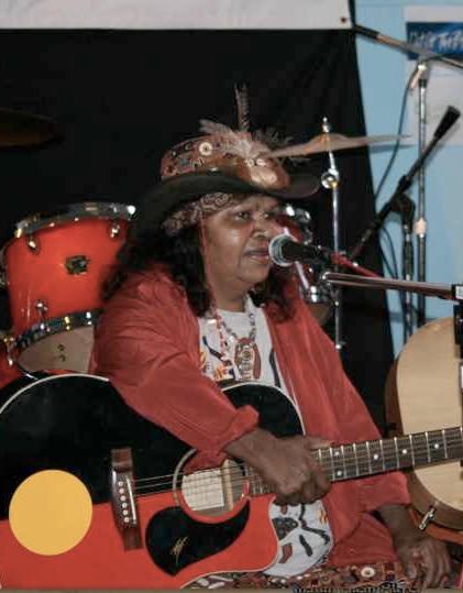 Photo of Ruby Hunter playing guitar and singing on stage