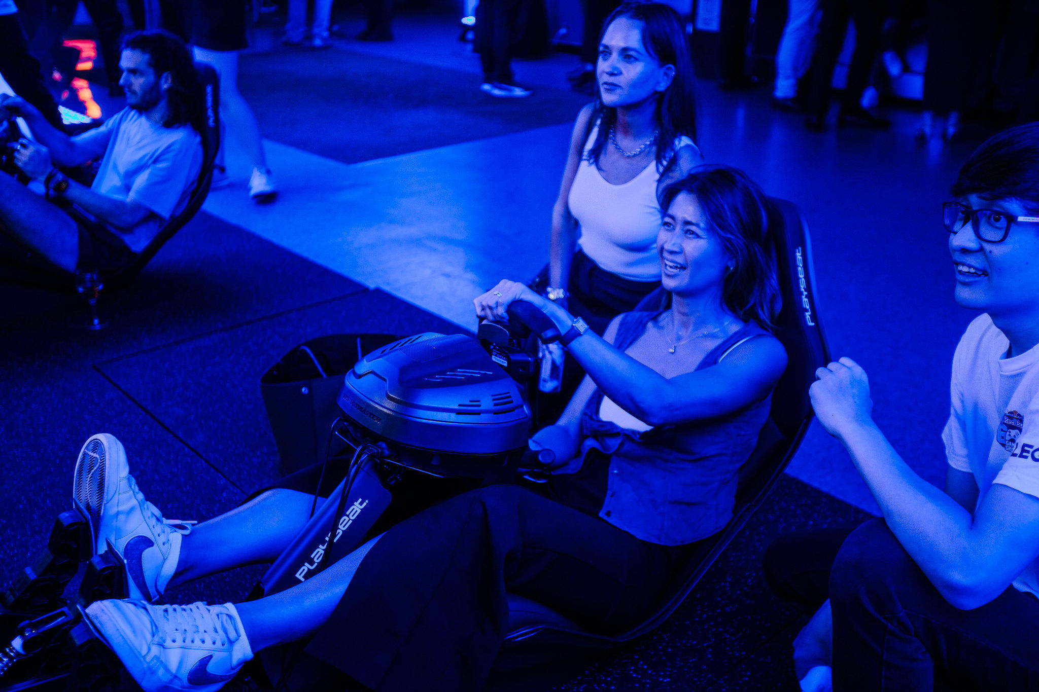 People playing a new video game with a seat and steering wheel component