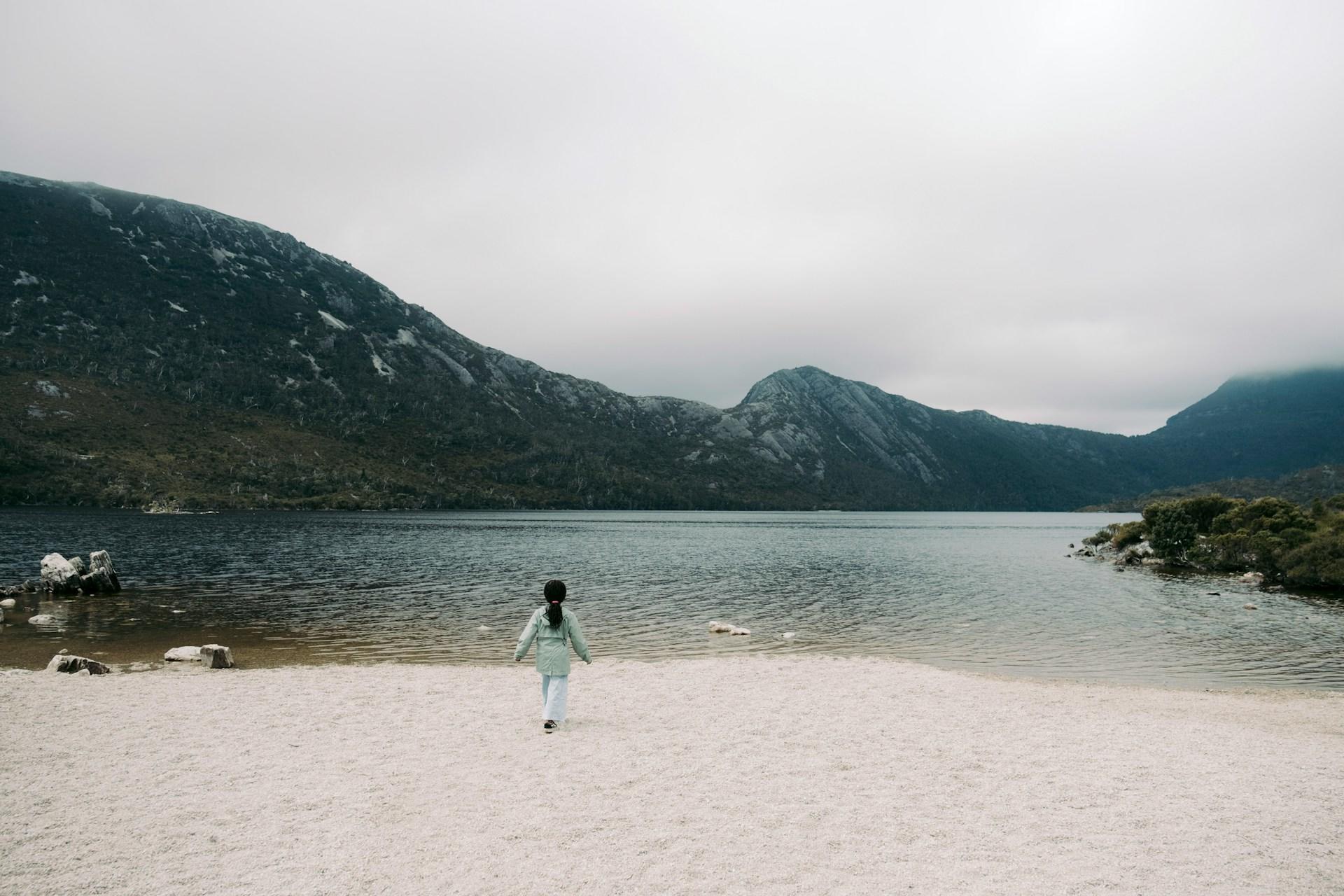 A person standing on a beach in Cradle Mountain, Tasmania.