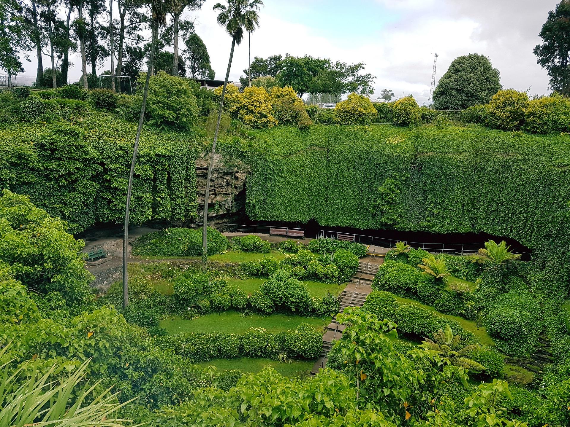 A sunken green space with trees and stairs on a cloudy day.  