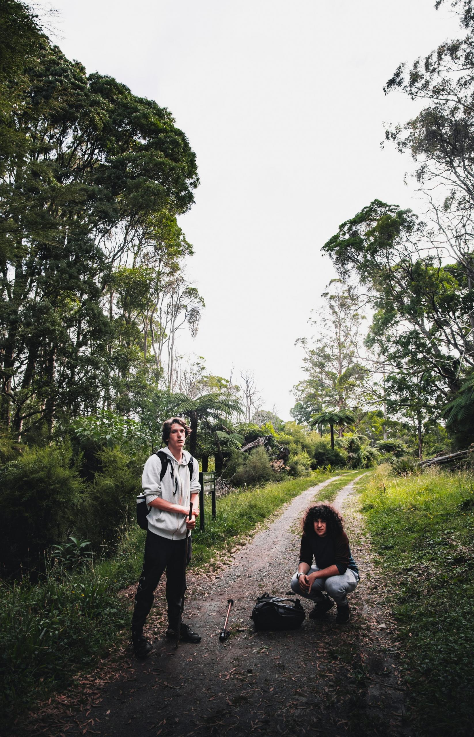 Two people with backpacks on a trail in a wilderness area.