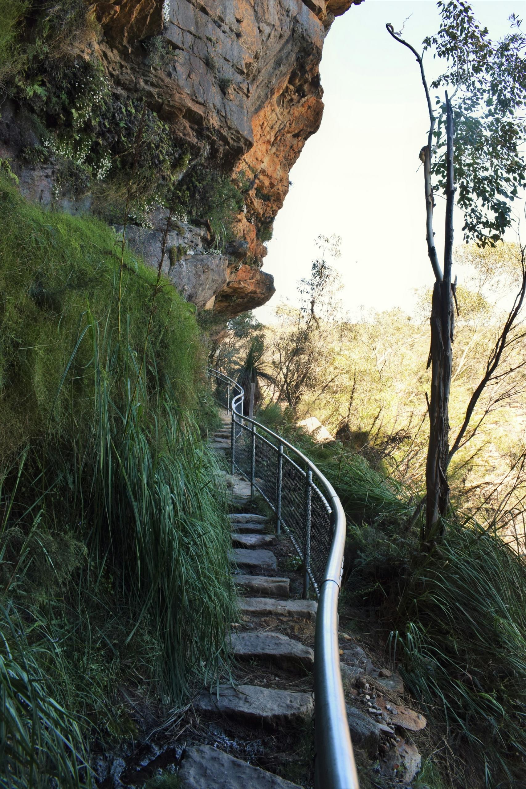 A staircase next to a cliff on a sunny day. 
