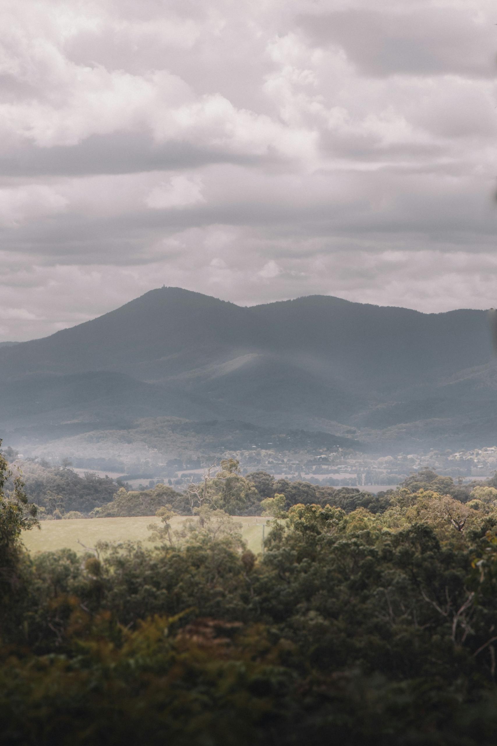A valley with mountains in the background on a cloudy day.