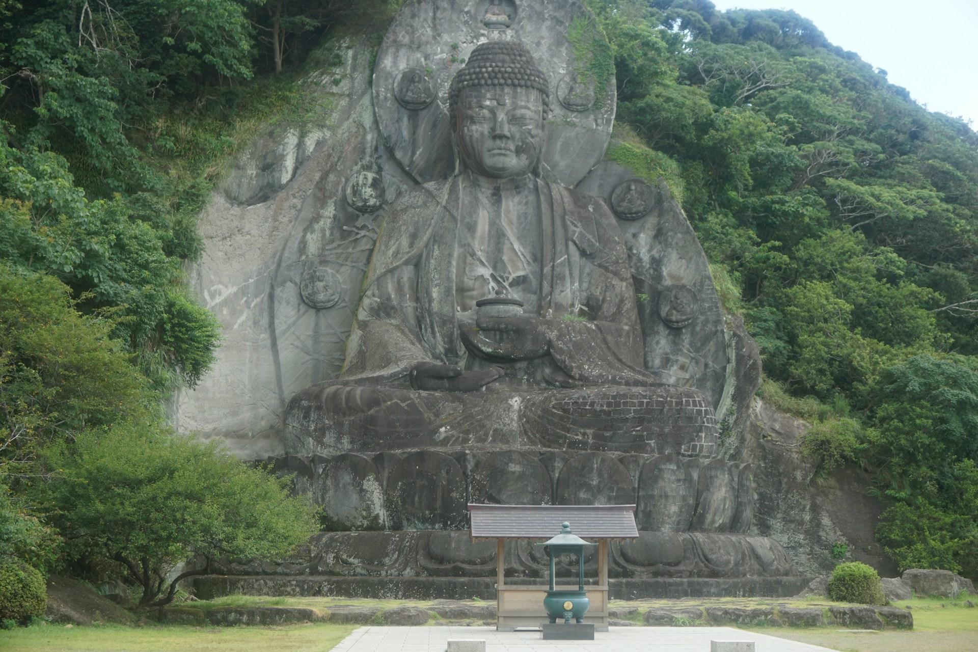 A giant stone buddha carved into a mountain on a cloudy day. 