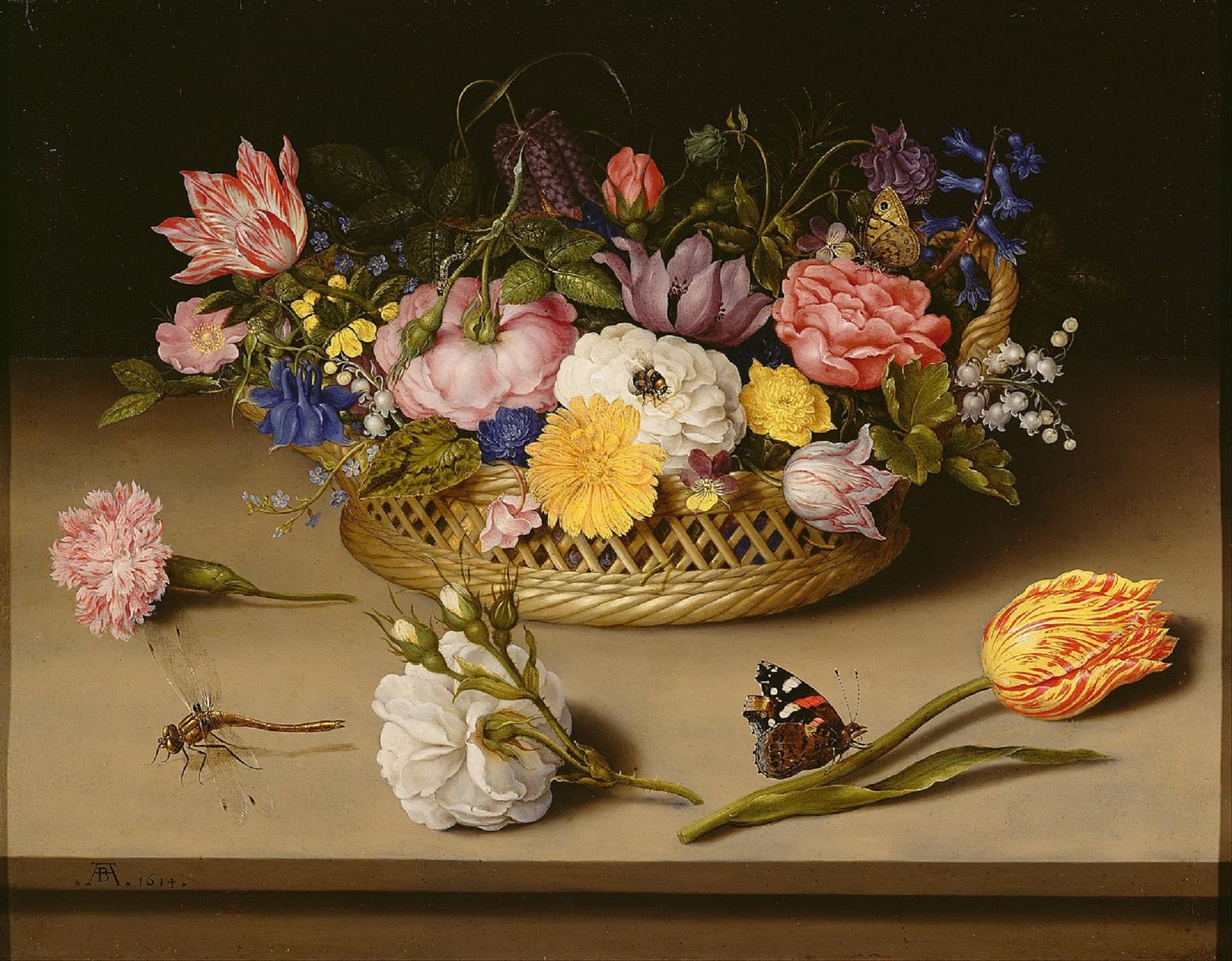 A basket of flowers on a brown surface, with three flowers laying on the surface itself.