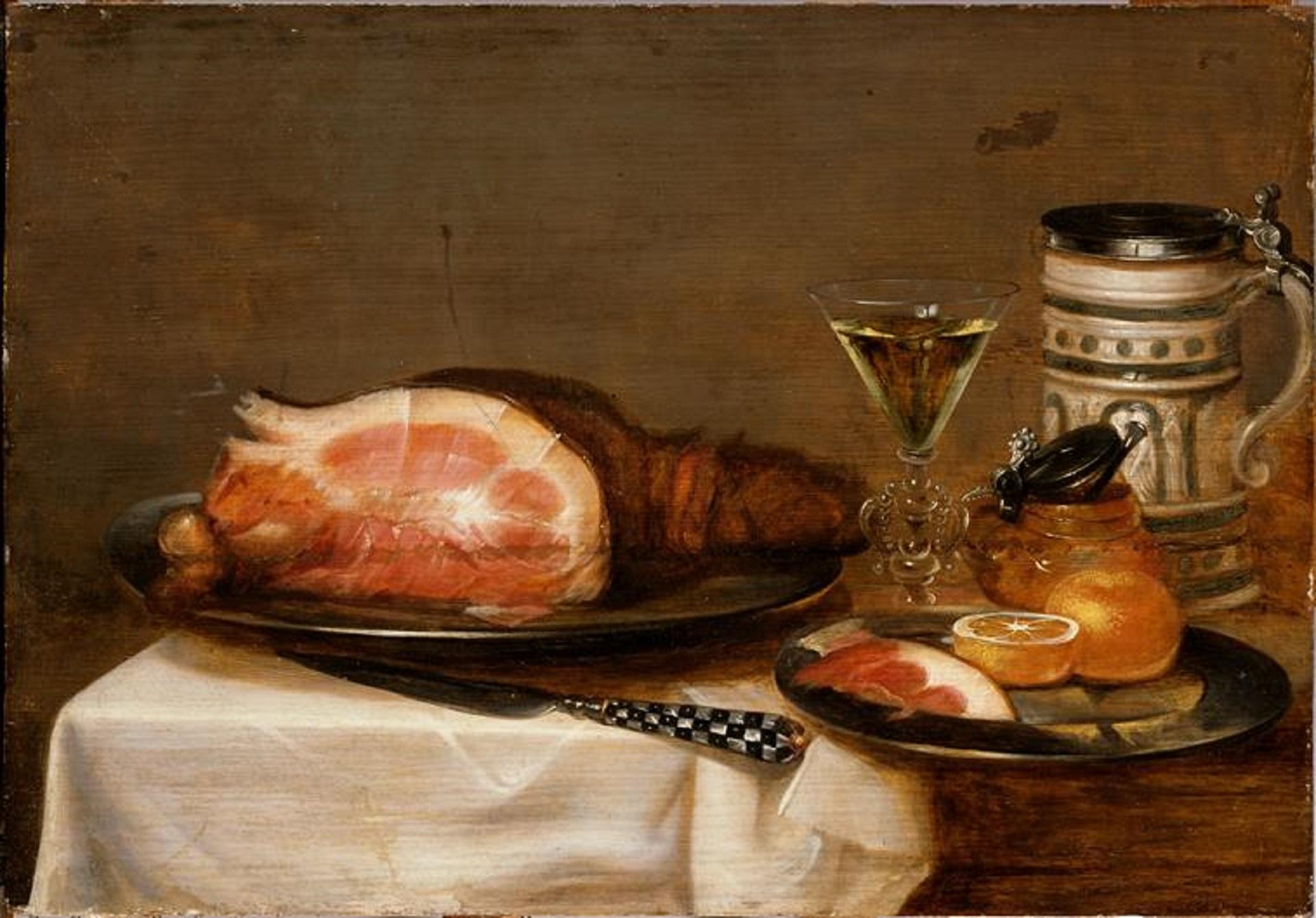 A ham laying on a platter next to a glass and a beer stein.