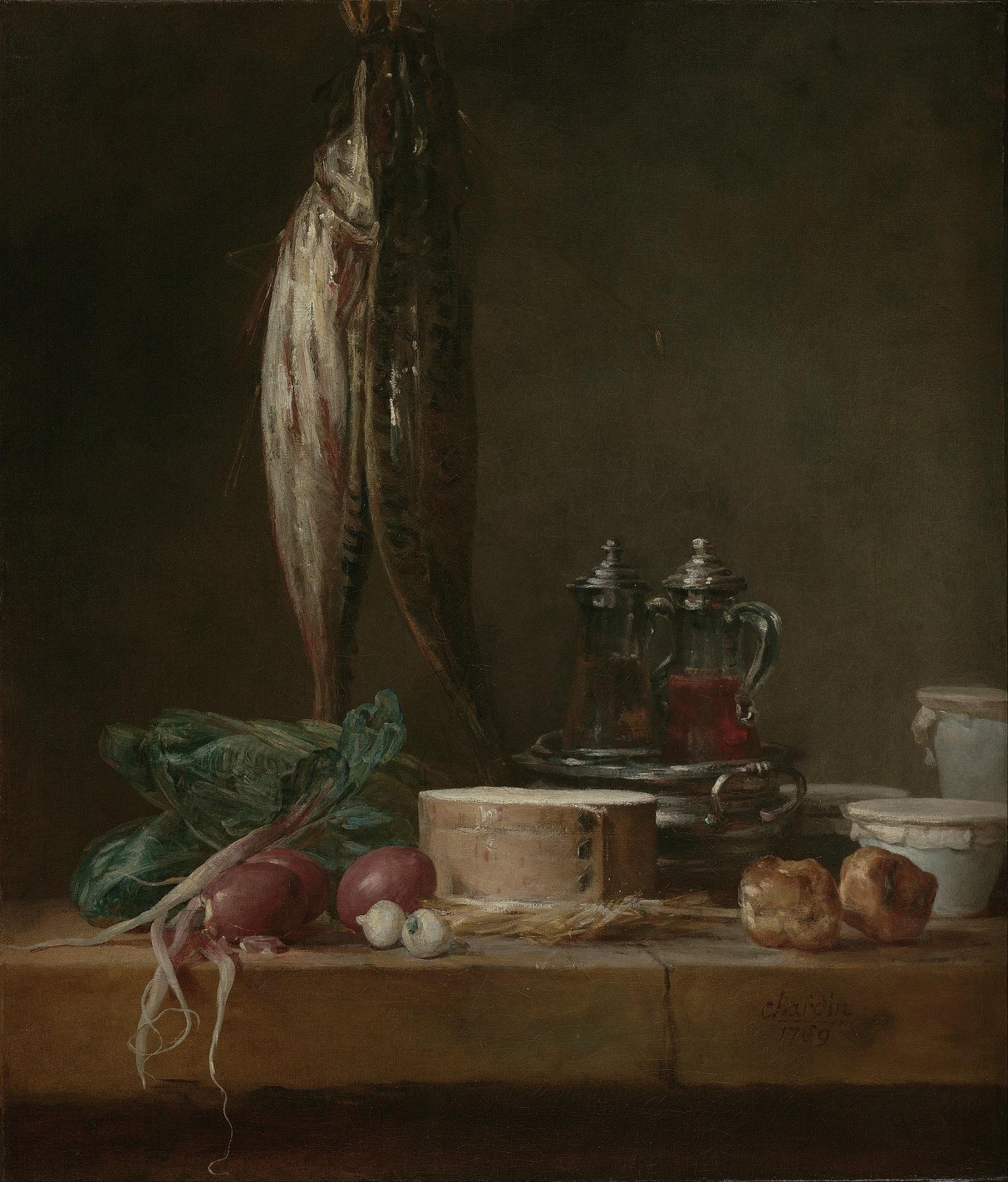 Two fish hanging over a table, which has vegetables and other food items on it.