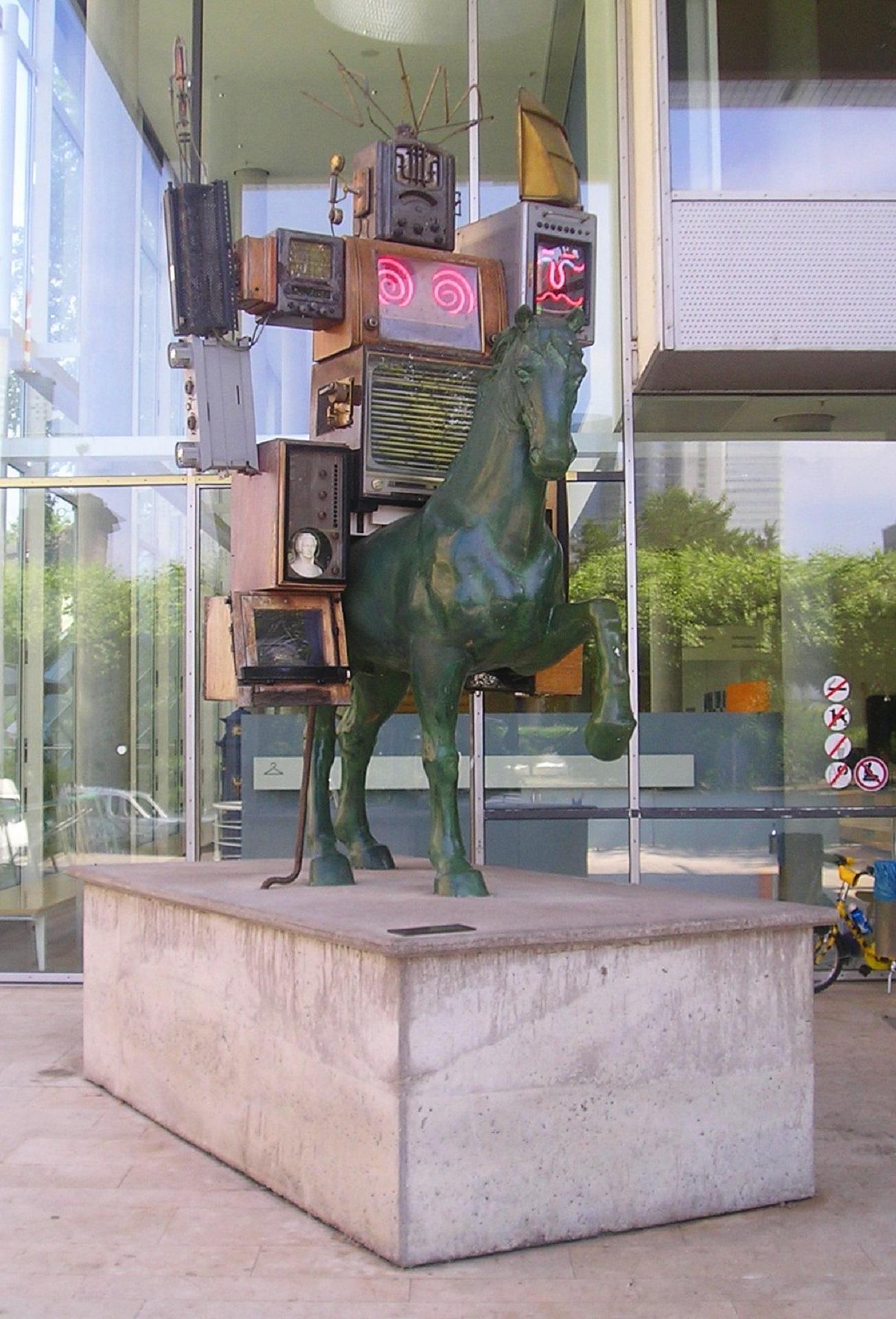 An art installation with a horse sculpture at its base and electronic equipment astride it.
