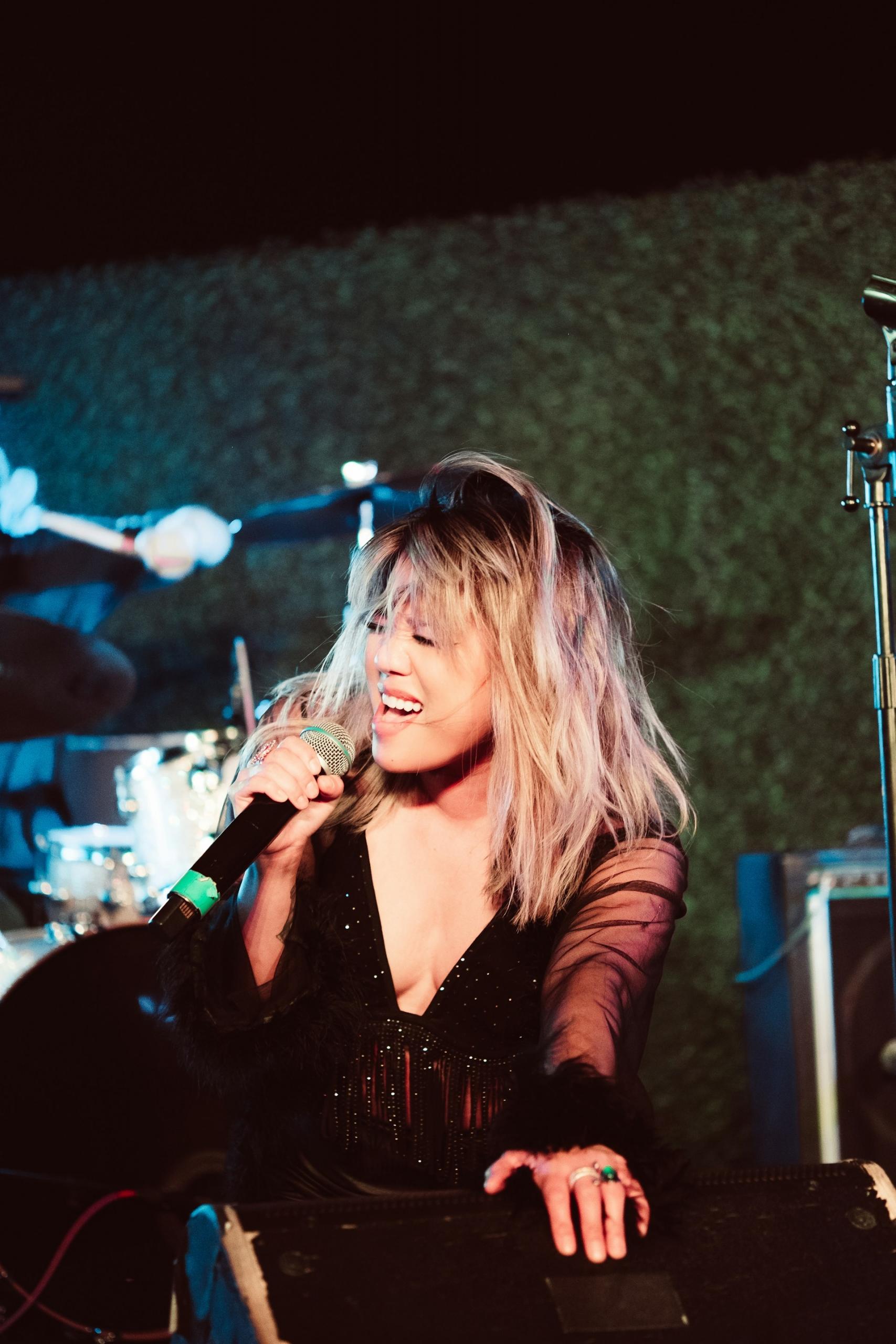 A woman with blond hair sings into a microphone.