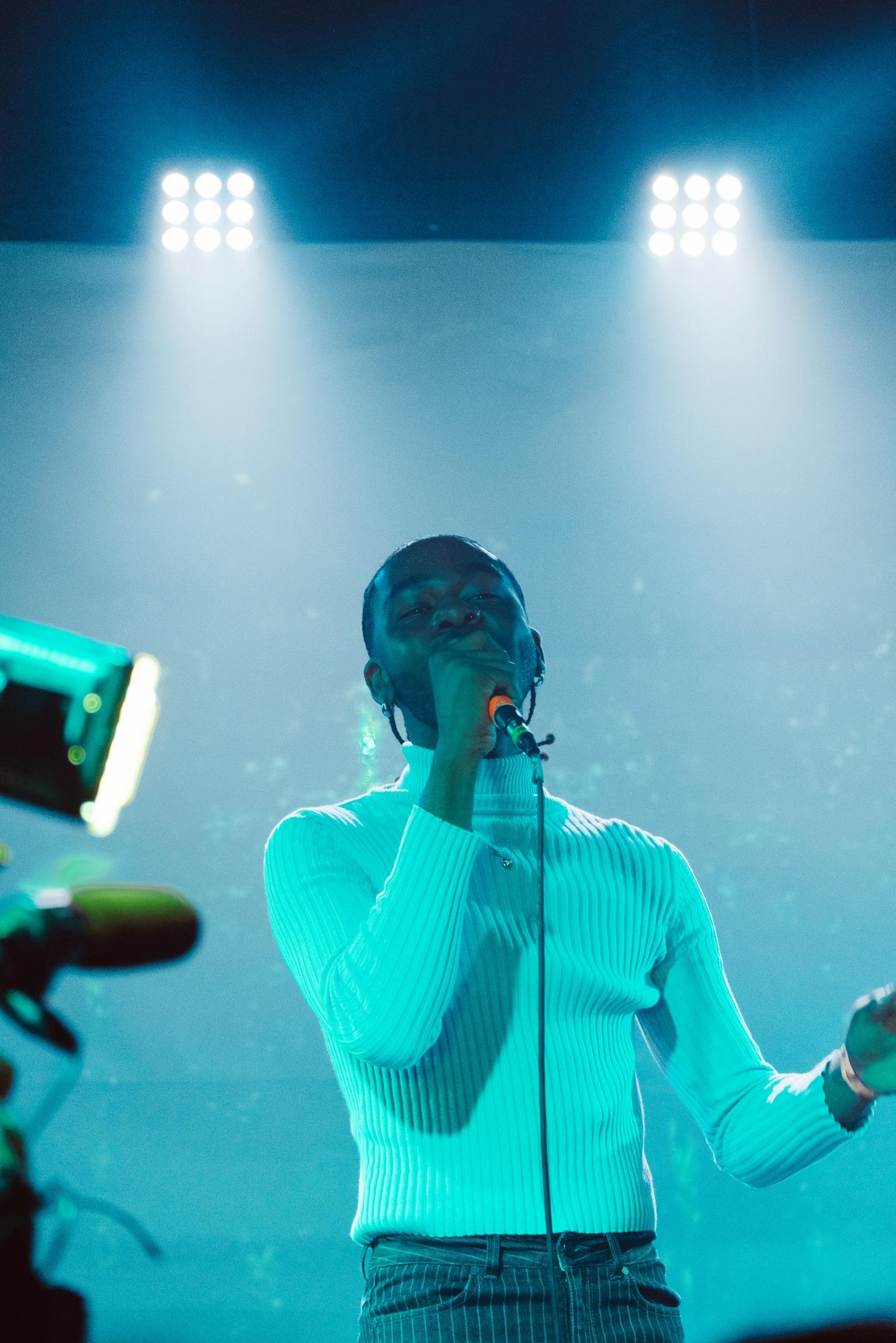 A man in a white jumper holding a microphone