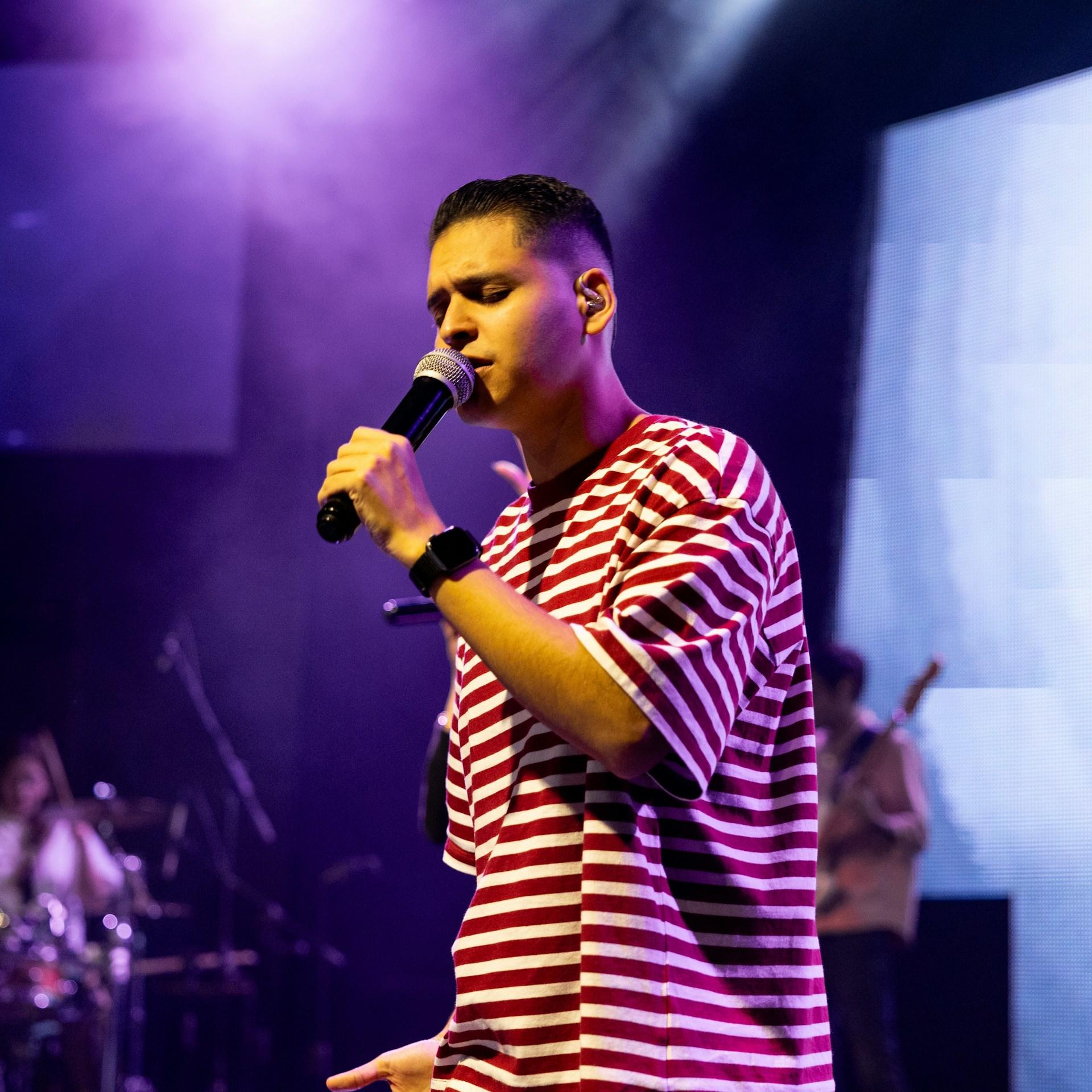 A man in a striped shirt holds a microphone. 