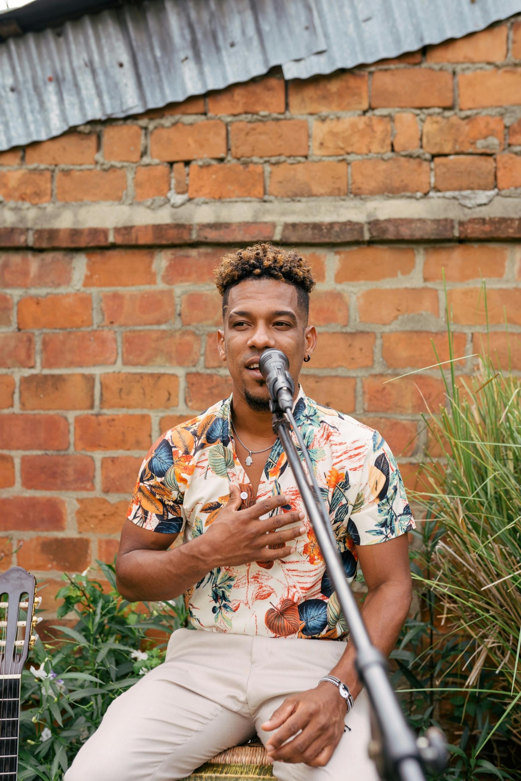A man in a patterned shirt sits behind a microphone.