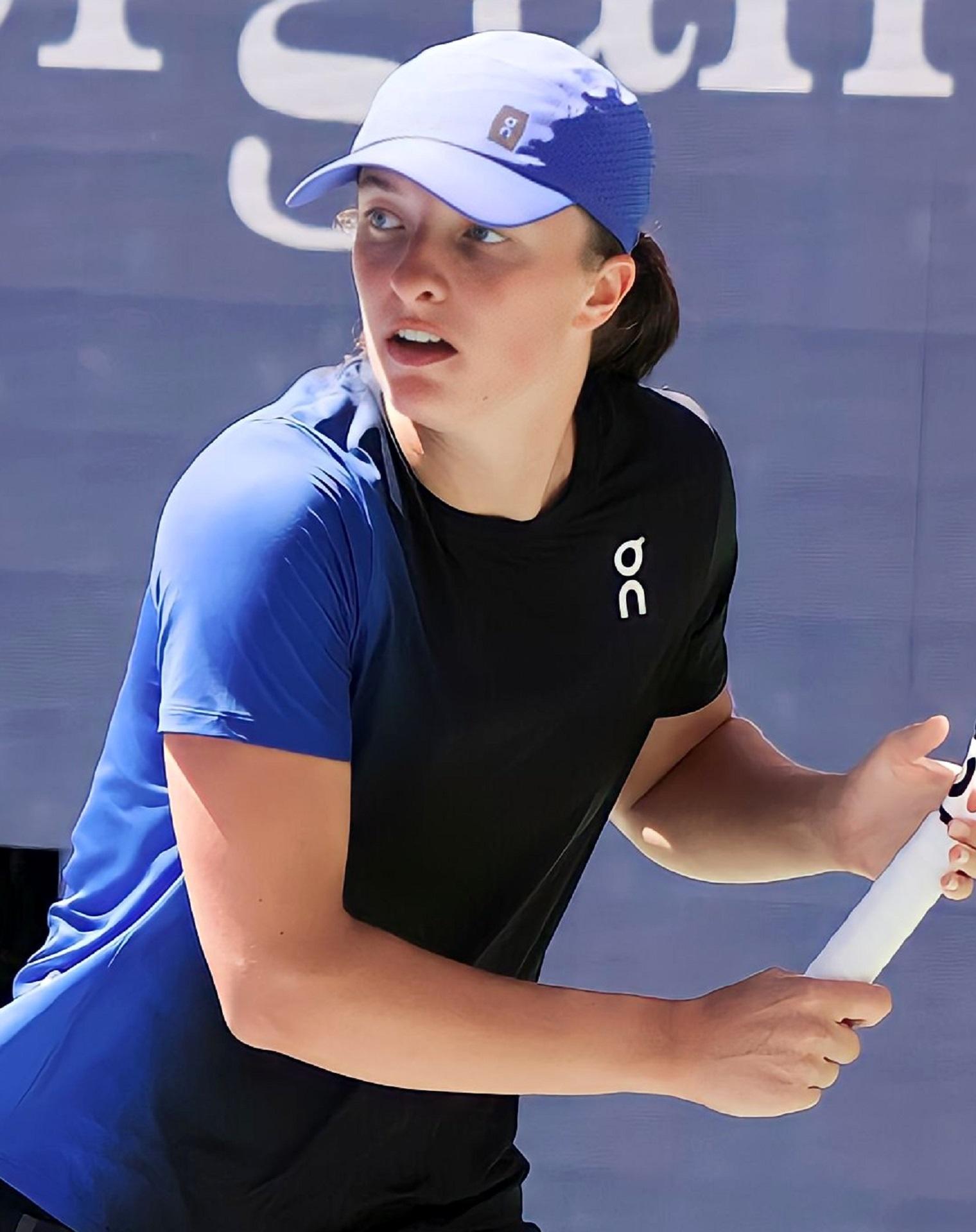 A woman wearing blue plays tennis on a sunny day.