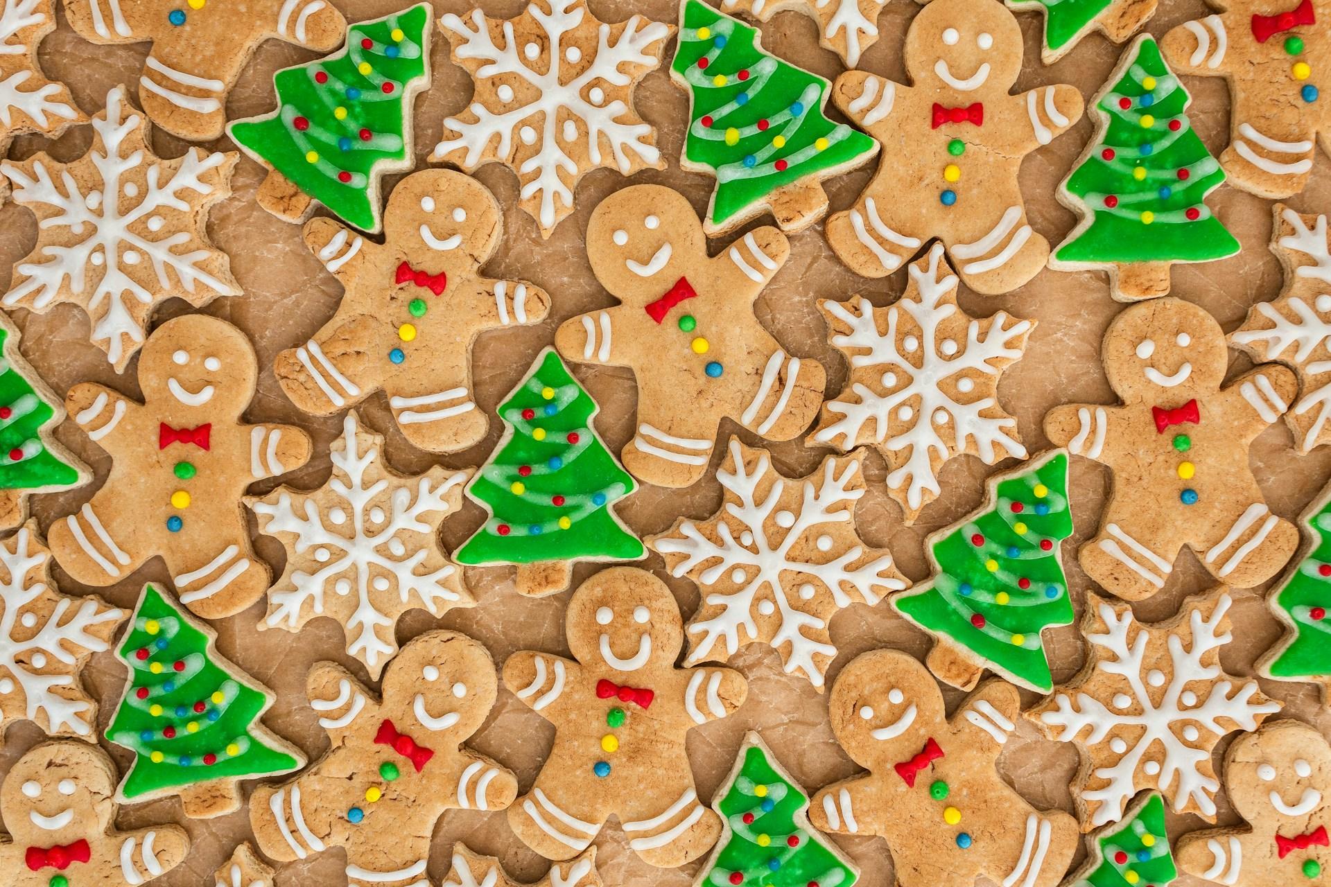 Assorted gingerbread cookies and snowflakes, some decorated as Christmas trees.