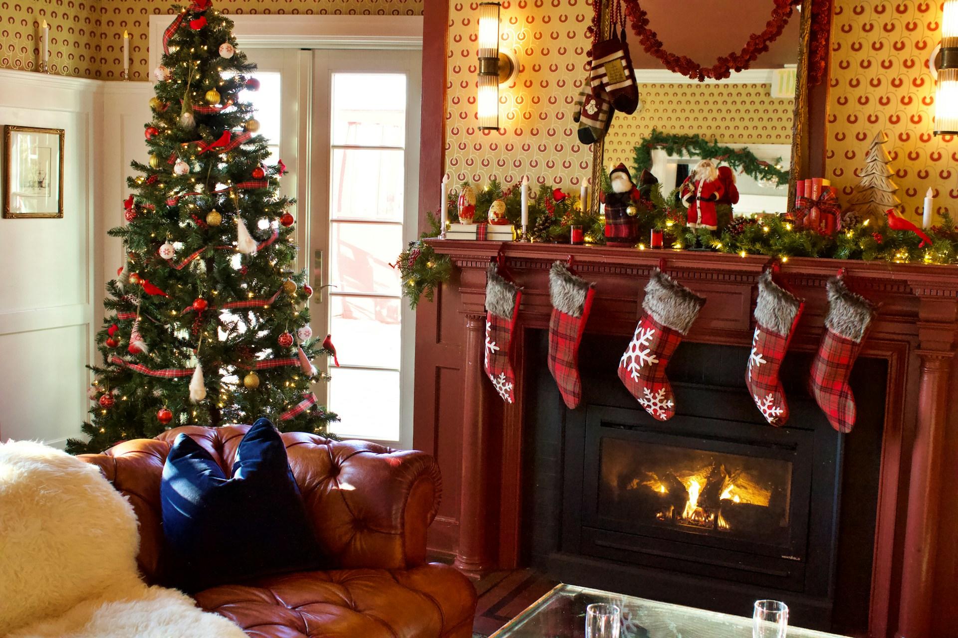 Cozy living room with a Christmas tree, stockings on a mantle, and a lit fireplace.